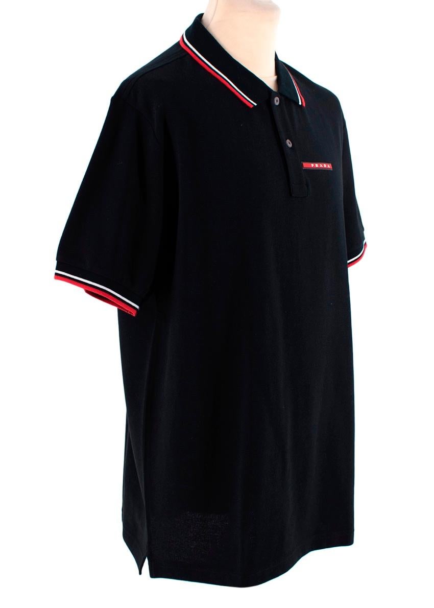 Prada Black Cotton Pique Contrast Trim Polo Shirt
 

 - Black pique cotton short sleeve polo shirt
 - Red and white colour trim detail to the spread collar and cuffs
 - Signature Prada red bar logo on the chest
 - Two button closure
 

 Materials:
