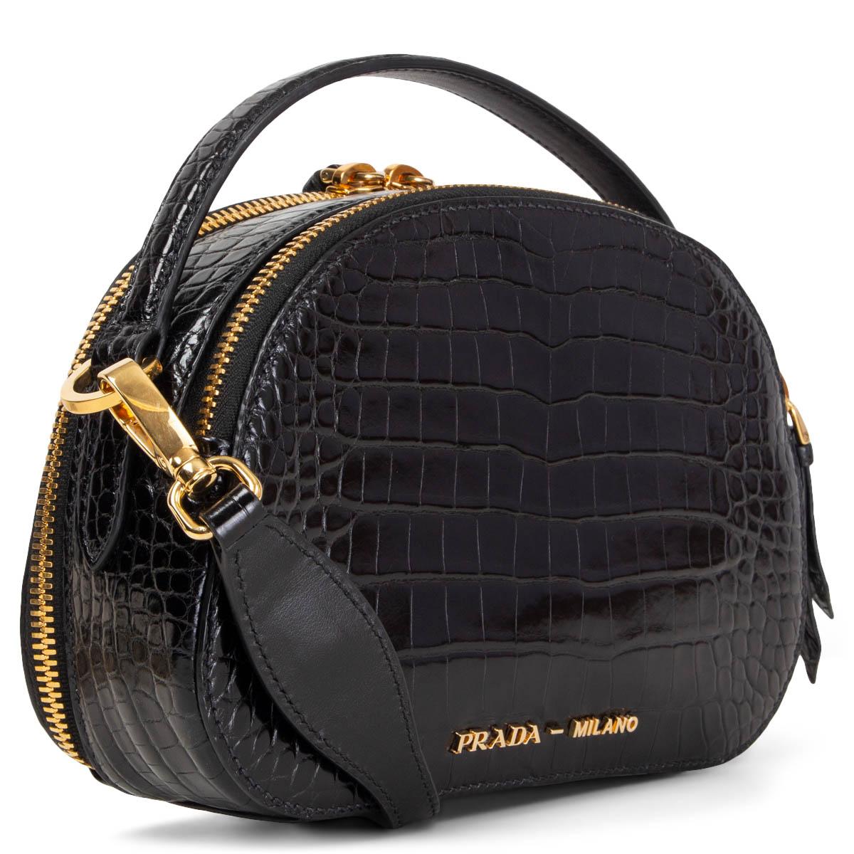 100% authentic Prada Odette Crocodile Bandoliera shoulder bag in black croco leather. Its dual zip compartments are lined with smooth black lambskin and equipped with one slip pocket. Comes with a detachable, adjustable shoulder strap and a top