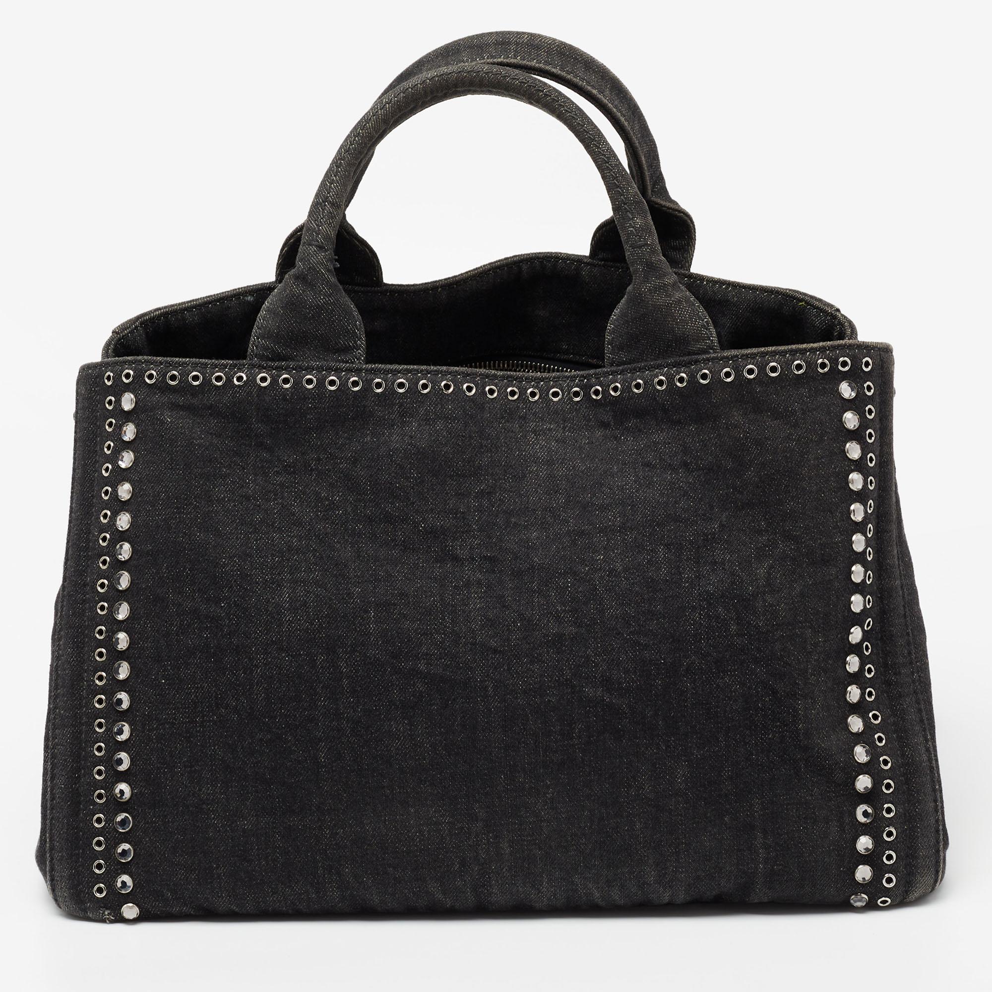 Coming from Prada is this black tote that is the perfect evening bag. It is crafted from denim into a structured shape and flaunts silver-tone hardware, crystal studs, dual handles, and a capacious interior for your belongings. The tote will look