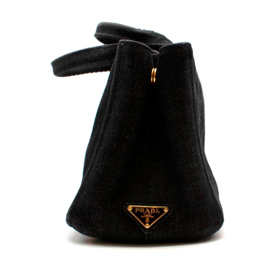 Prada Black Denim Vintage Inspired Gardener's Tote

A vintage-inspired gardener's bag. Printed with a silk-screen logo and embellished with brass-finish hardware, it offers three practical internal pockets.

- Denim handles
- Gold tone metal
