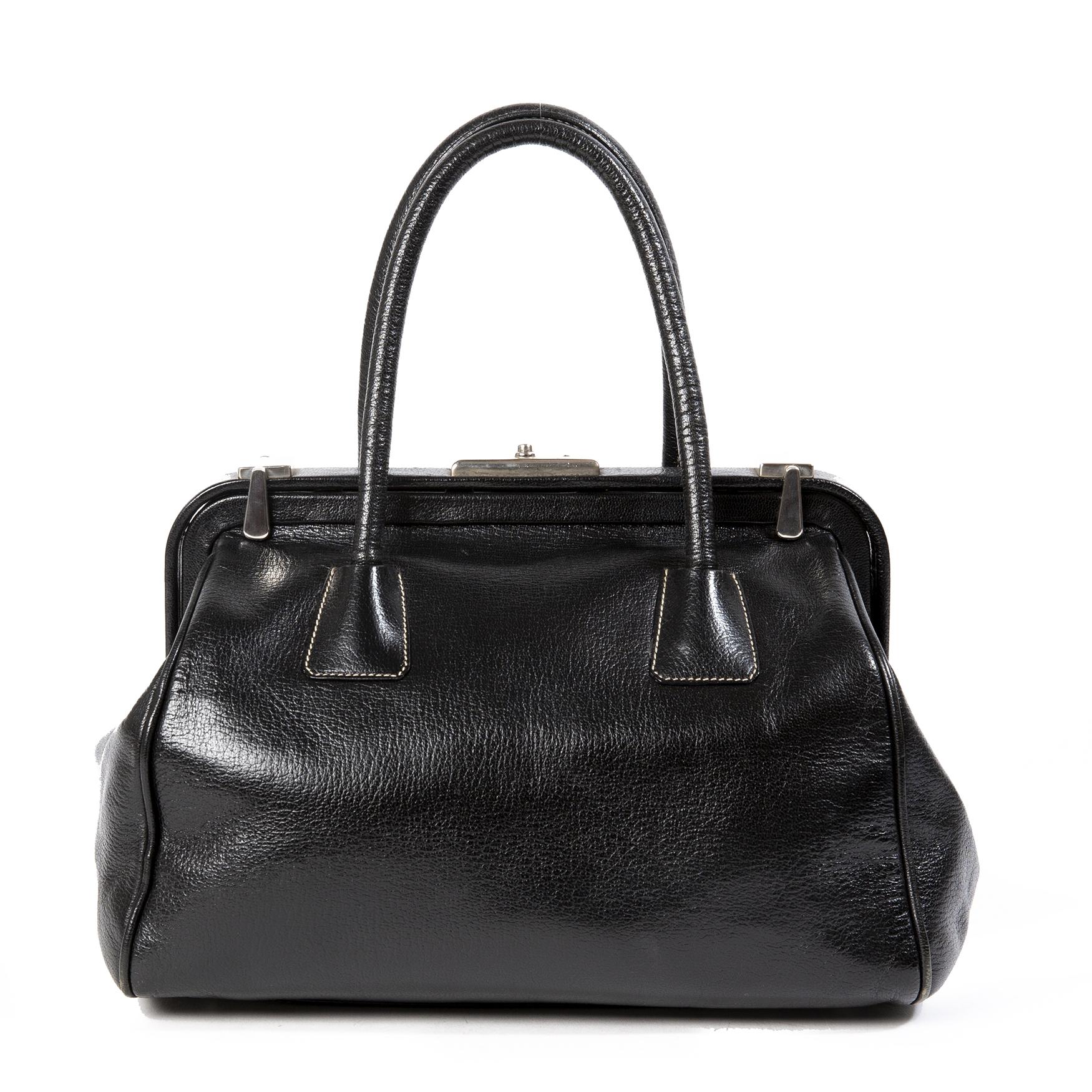 Good condition

Prada Black Doctor's Bag

This gorgeous Prada bag is crafted from black leather and features two rolled top handles.
It has a doctor's bag shape and silver-tone hardware. The interior is fabric lined and features one zip pocket.
