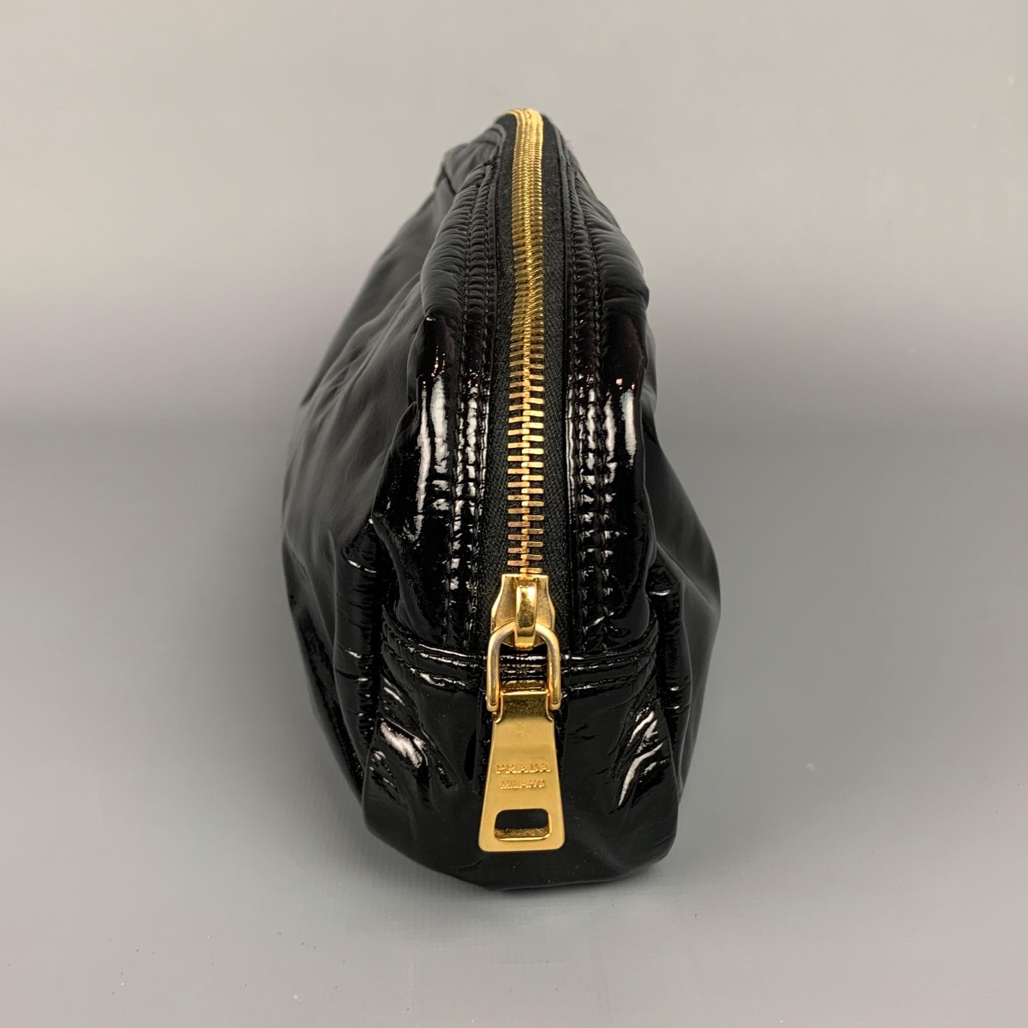 PRADA pouch comes in a black faux patent leather featuring gold tone hardware and a zipper closure. 

Very Good Pre-Owned Condition.

Measurements:

Length: 12 in.
Width: 2 in. 
Height: 4.5 in. 
