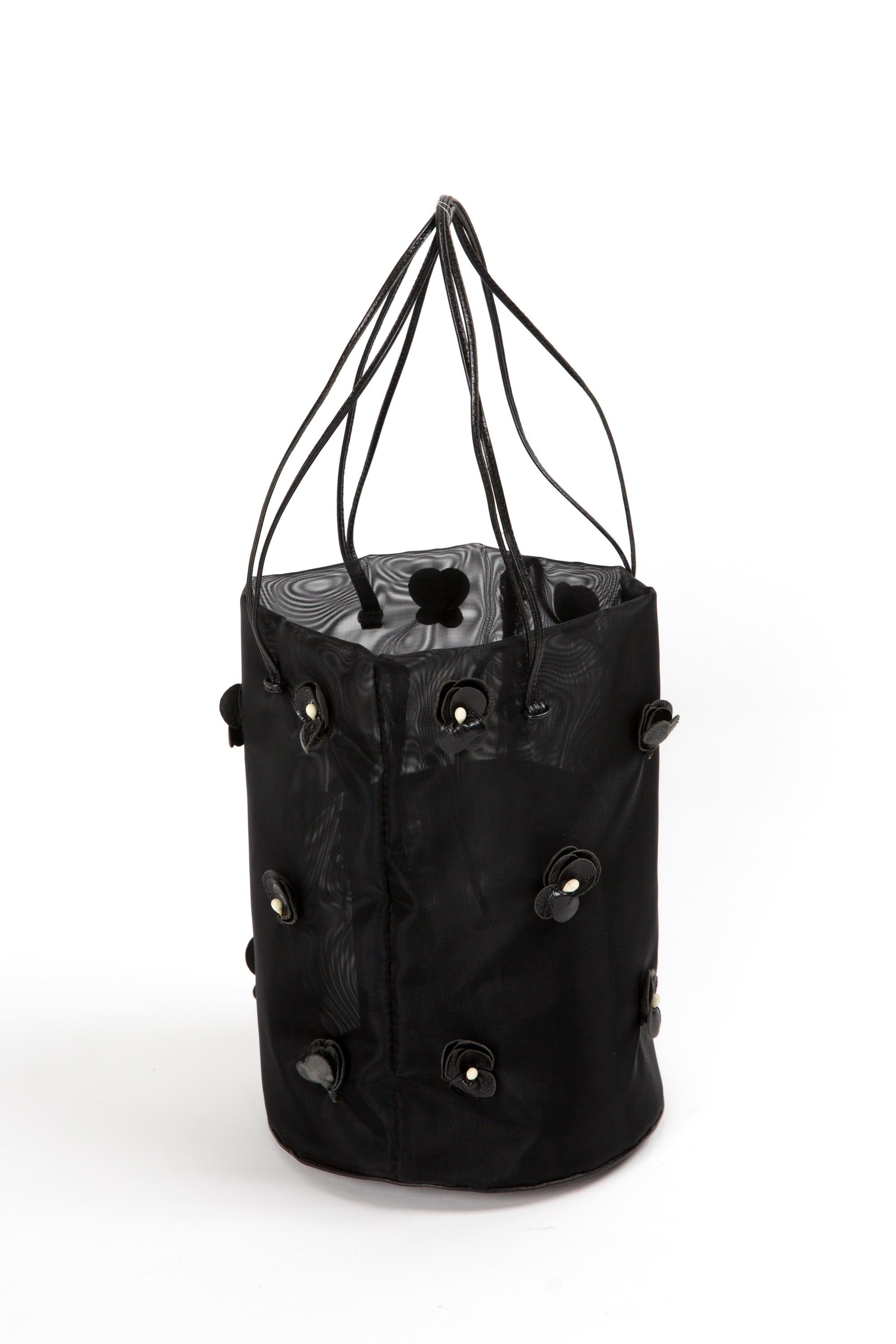 Prada black floral mesh bucket bag featuring black nylon mesh with leather floral embellishments, Silver tone hardware, black mesh lining and an inner leather zipper pouch.
Circa 2000s.  
In good vintage condition. Made in Italy.
Length: 5.9in.