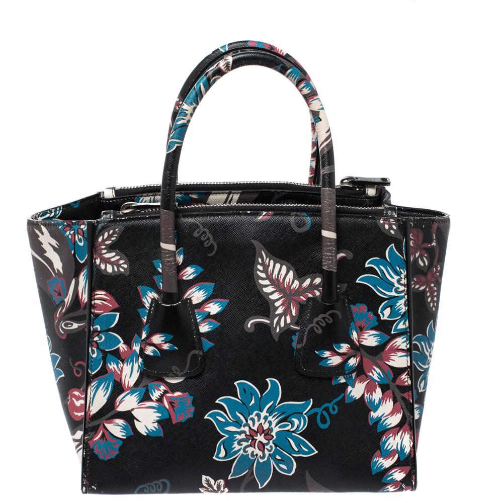 Mit ihrer femininen Form und ihrem großartigen Design wird diese Doppelreißverschluss-Tasche von Prada eine beliebte Ergänzung für Ihren Kleiderschrank sein. Es wurde aus Saffiano-Leder mit Blumendruck gefertigt und mit silberfarbenen Beschlägen