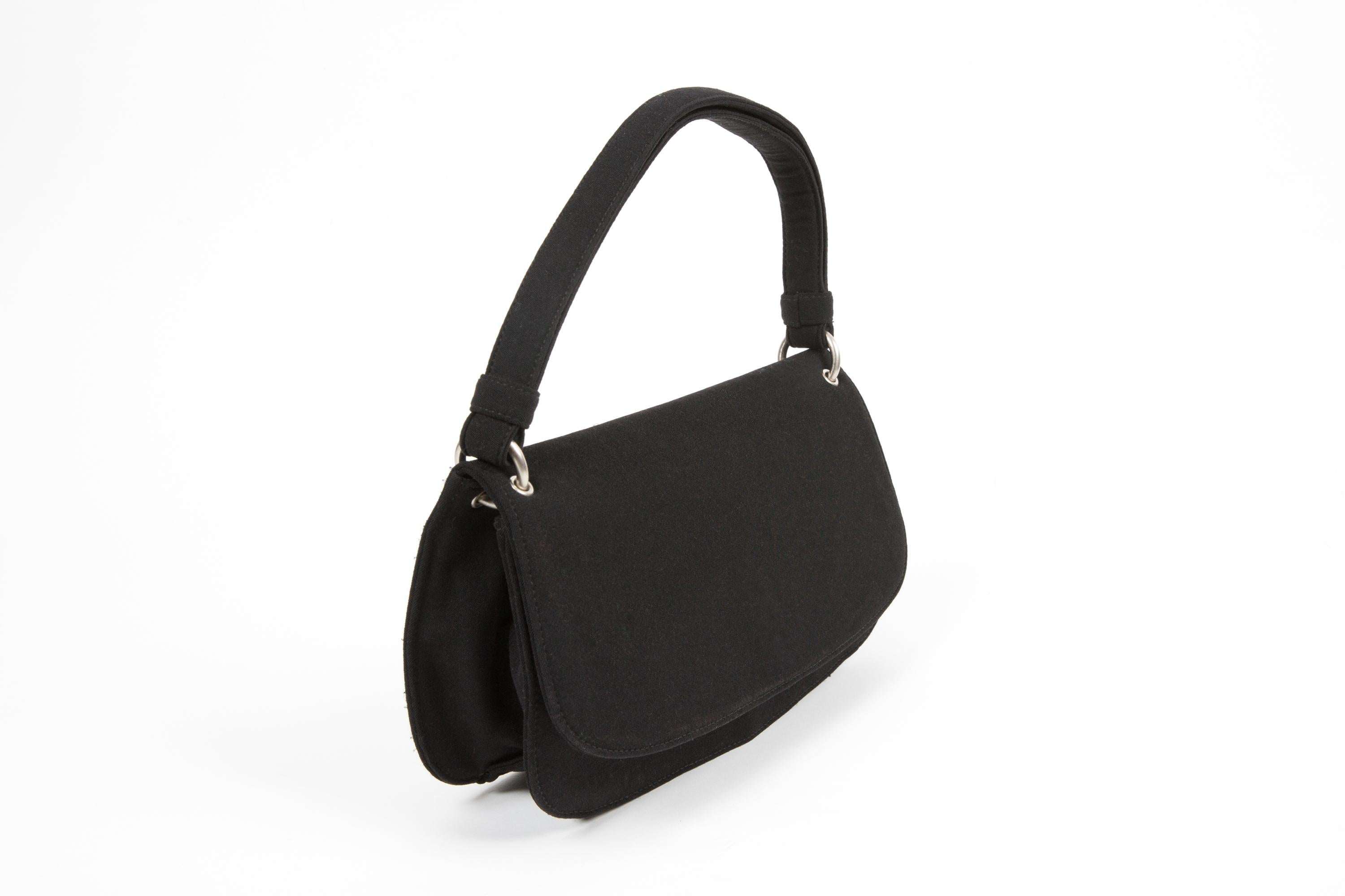 Prada Black canvas handbag featuring a snap closure inside zipped flat pockets, silver-tone hardware, interior logo lining and inside the enameled metal plaque.
Circa 2010s. 100% Nylon
In good vintage condition. Made in Italy.
Length: 11.8in. (30cm)