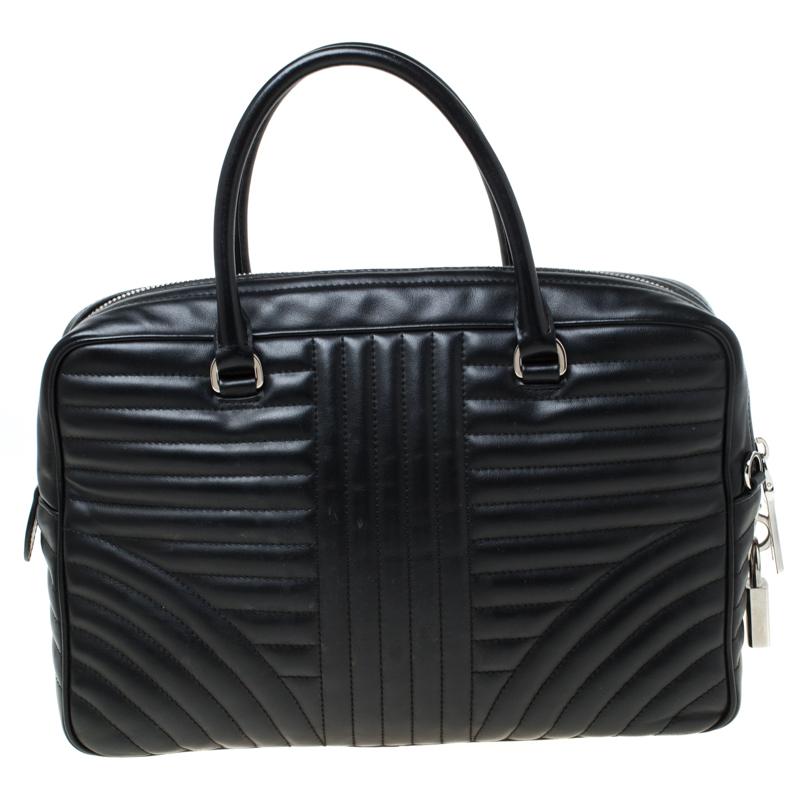 This Prada creation is stylish and handy. The bag has been crafted from leather in a lovely black shade and equipped with two top handles, a removable shoulder strap and a padlock with a key holder. The top zip closure opens to a nylon lined