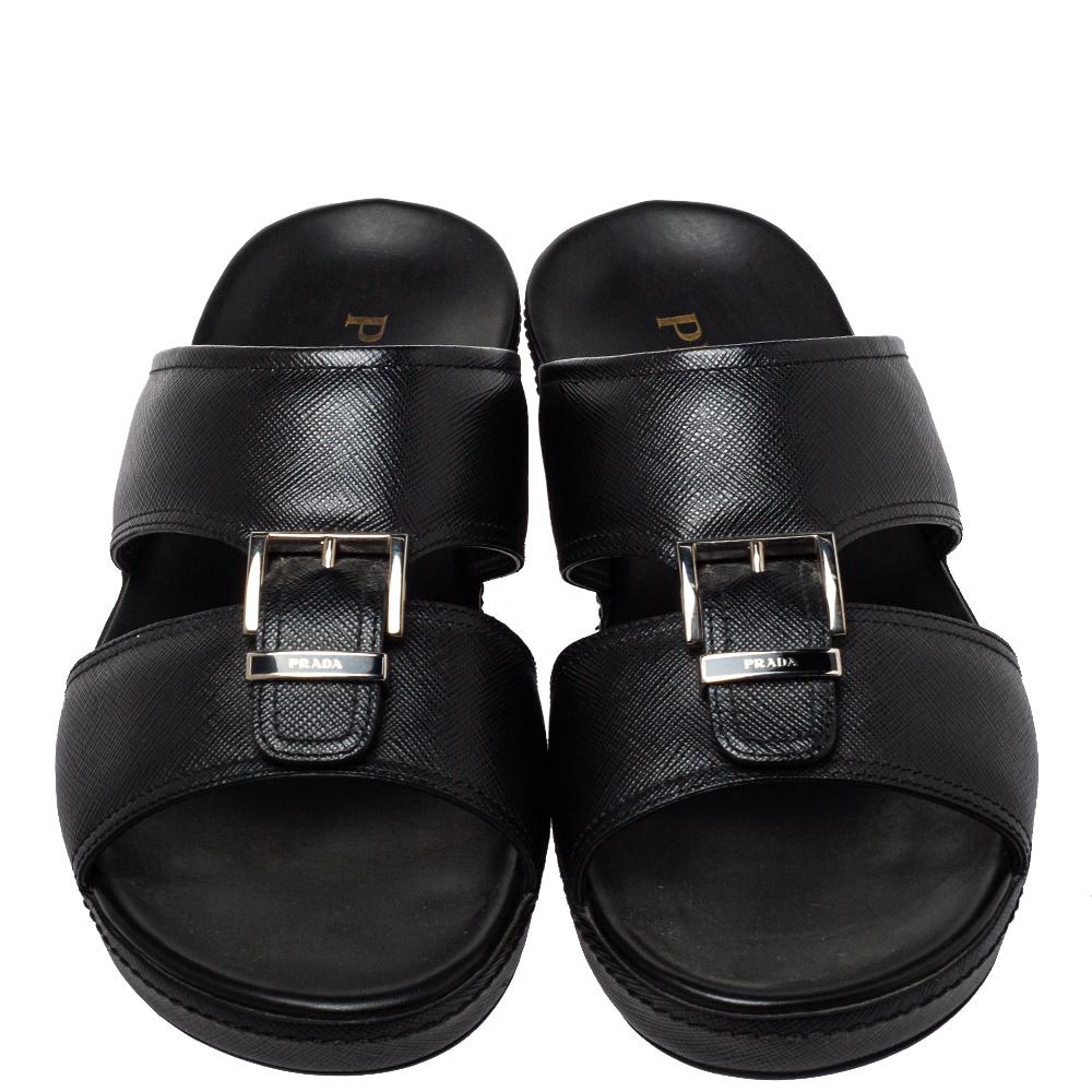 These stylish slides by Prada will make sure your casual dressing is on point. Crafted from leather, they come in a classic shade of black. They are styled with open toes, buckle detailing on the vamps, gold-tone hardware, and durable rubber soles.

