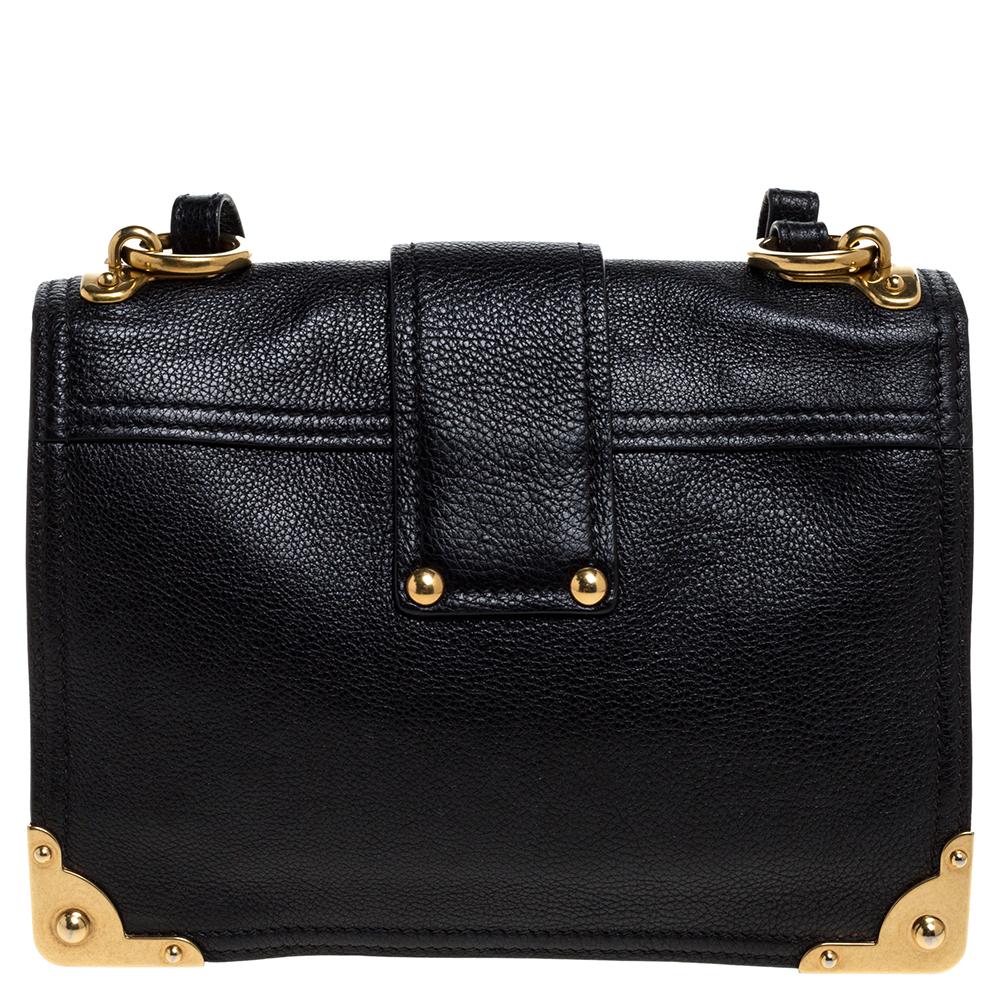 Inspired by valuable books from ancient times, the Cahier by Prada is a best-seller. This shoulder bag is crafted in Italy with black leather. It features gold-tone trims that add a touch of contrast. The strap closure with the brand logo opens to a