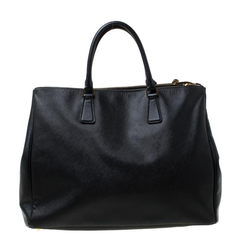 Fashioned in a black leather body, this Prada Executive Double Zip tote is spacious and stylish at the same time. It features an open top with two zip compartments on each side. It features a gorgeous leather interior and comes with a zipper pocket