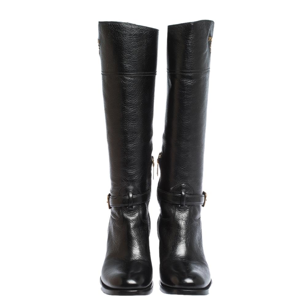 Prada elevates your style quotient by giving you just the right amount of luxury with this gorgeous pair of black boots. They are cut to a knee-length and feature round toes, buckle and logo detailing in gold-tone and low heels.

Includes: Info