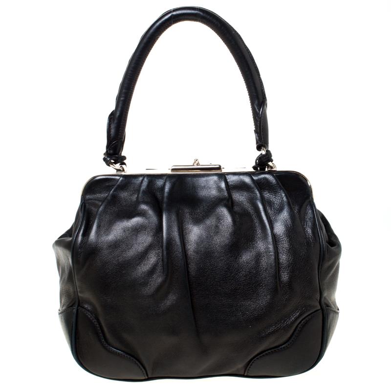 This well-designed satchel from Prada is crafted from black leather with silver-tone metal framed top. The exterior of the bag is adorned with subtle pleats, tassels and a leather tag. It has a nylon-lined interior featuring a zip pocket. Held by a