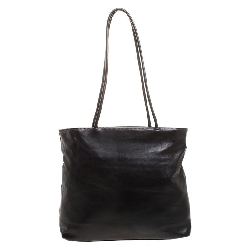 Smoothly glide from day to night with this versatile leather bag that offers a superior design. Equipped with a fabric interior and two handles, it is luxurious enough to elevate your everyday style. The black bag is by Prada and it is designed to