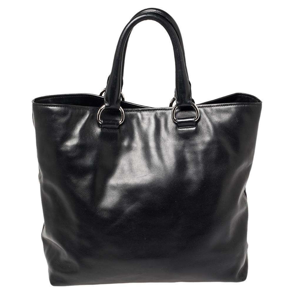 Turn heads when you go out carrying this beautifully crafted bag from Prada. Carry this black bag to your next event for a statement-making impression. It is crafted from leather and is styled with dual handles, logo detailing in the front, and a