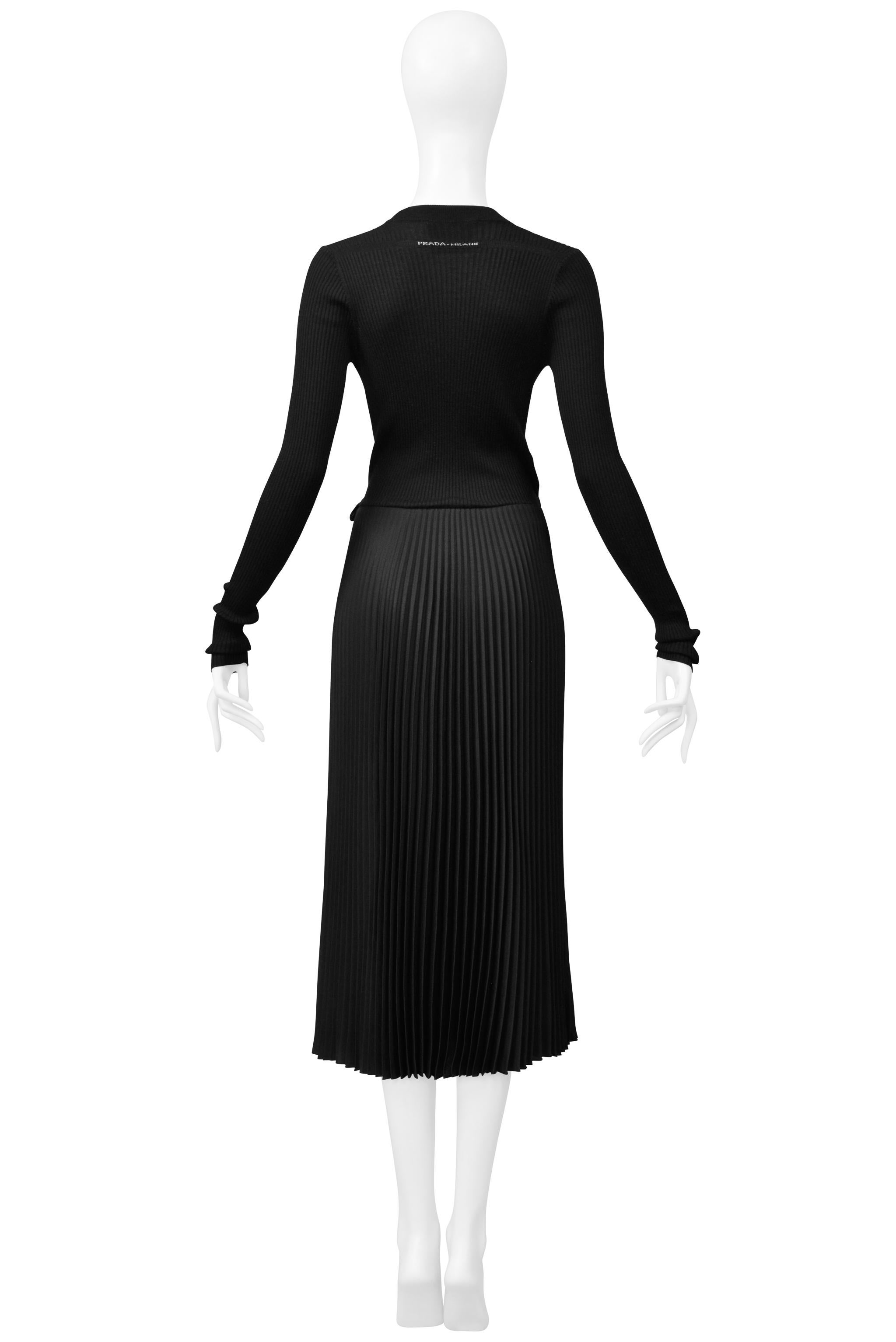Resurrection Vintage ist begeistert, ein klassisches, schwarzes Prada Strick-Wickelkleid mit plissiertem Rock, langen Ärmeln, Prada Milano Aufdruck am äußeren Rückenausschnitt und einer Länge unterhalb des Knies anzubieten. 

Prada

Größe: 40