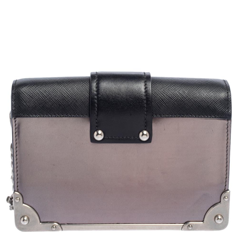 Inspired by valuable books from ancient times, the Cahier by Prada is a best-seller. This bag is crafted in Italy with black and metallic-hued leather. It features a silver-tone loop at the front that adds a touch of contrast. The strap closure with