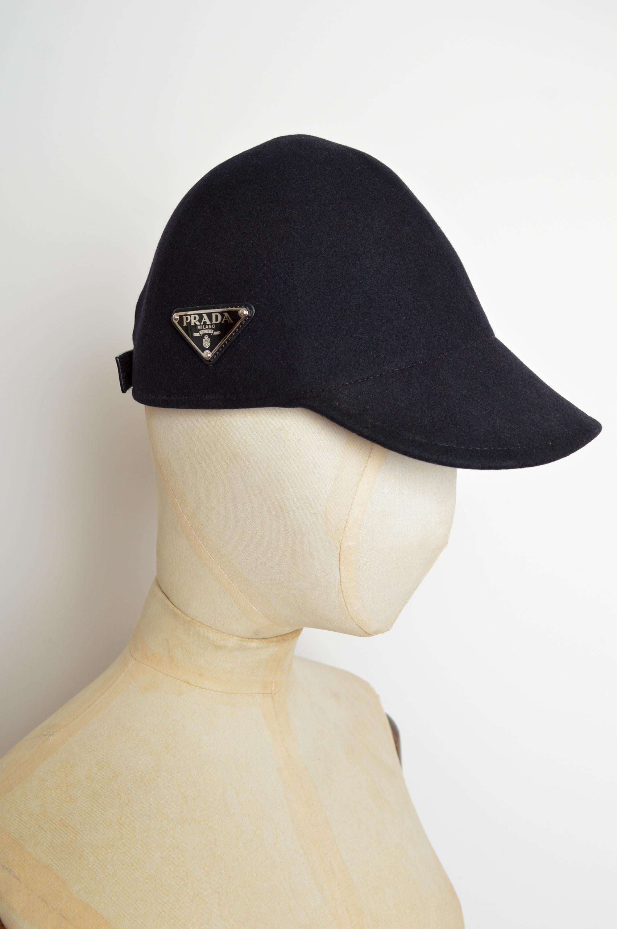 PRADA Almost Black (blu navy notte) Berretto in lana cashmere stile cloche con l'iconico logo Prada sul lato e chiusura in pelle con velcro. Una cima bassa che può quasi nascondere gli occhi.
Taglia; TAGLIA UNICA 
Le misure sono indicate in pollici