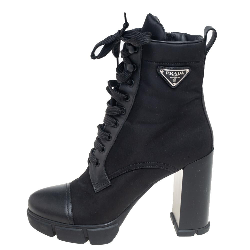 These fashionable Prada ankle boots made of black nylon and leather offer a sleek style and durable quality. They feature simple laces, round toes, the triangular Prada logo on the side, and block heels supported by platforms. They've been designed