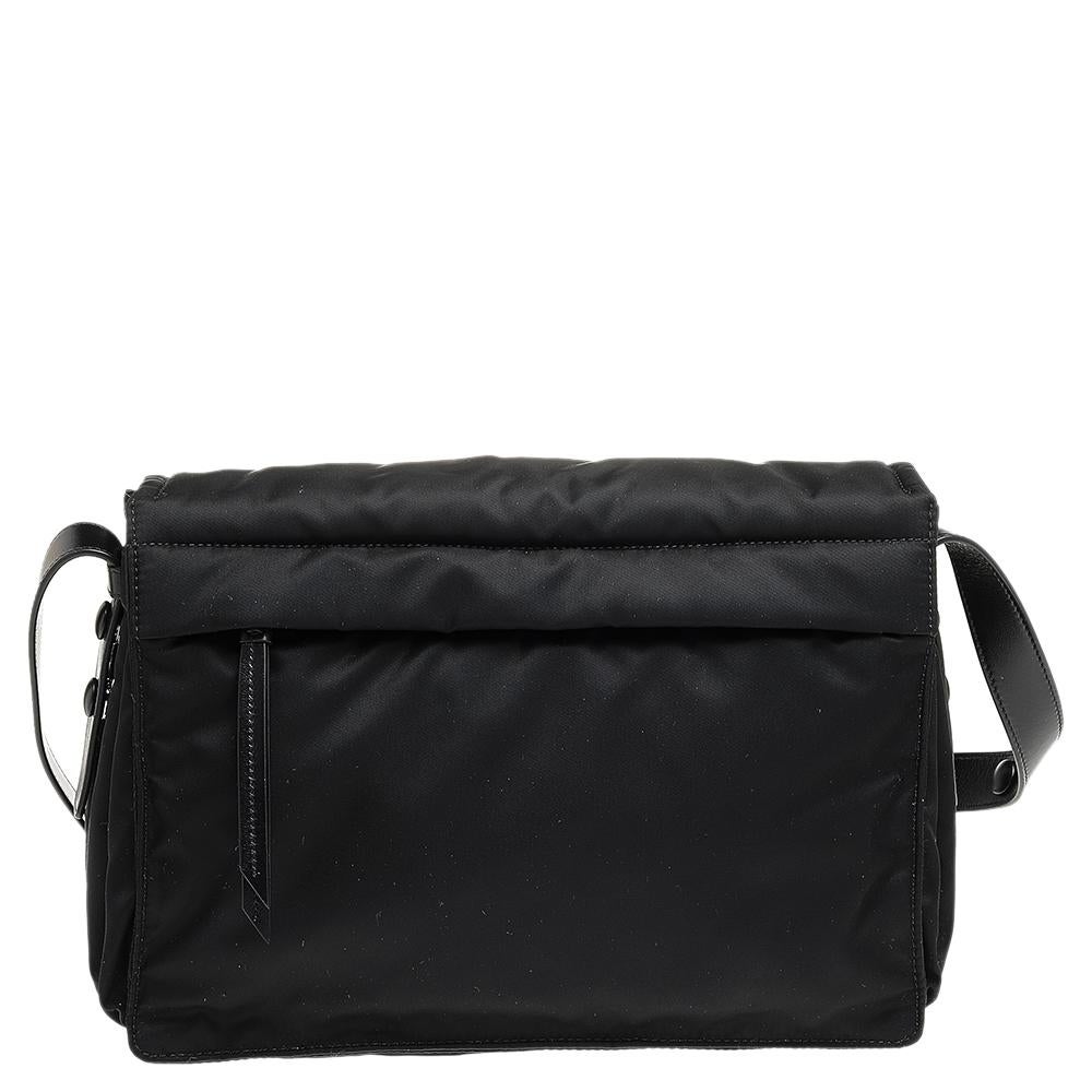 This shoulder bag from Prada is a timeless piece. The bag comes in a luxurious black nylon & leather exterior with silver-tone hardware. It features a shoulder strap with the brand logo at the front. It opens to a spacious interior that will easily
