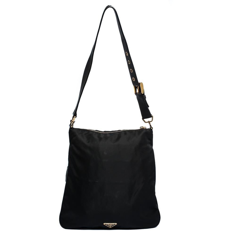 Prada presents a meticulously crafted handbag for everyday use. Made from quality nylon and leather, it comes in a classic shade of black. It has a slouchy silhouette, a single shoulder handle, zip closure and a spacious nylon-lined interior. It has