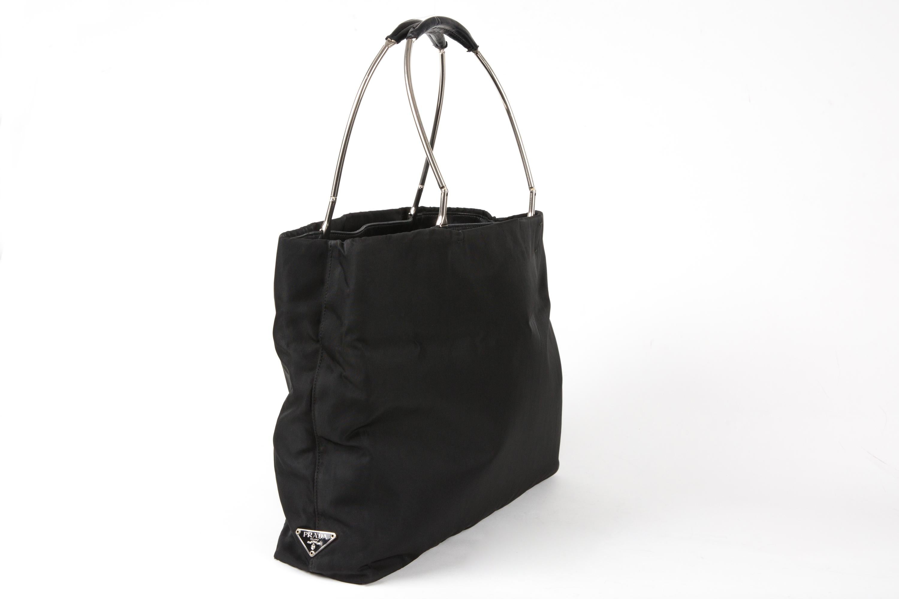 Prada Black nylon Tessuto handbag featuring at side the enameled metal triangle logo, top silver-tone metal and leather handles, inside leather parts, bottom leather part, inside compartments, interior inside compartments with zipper pocket, inside