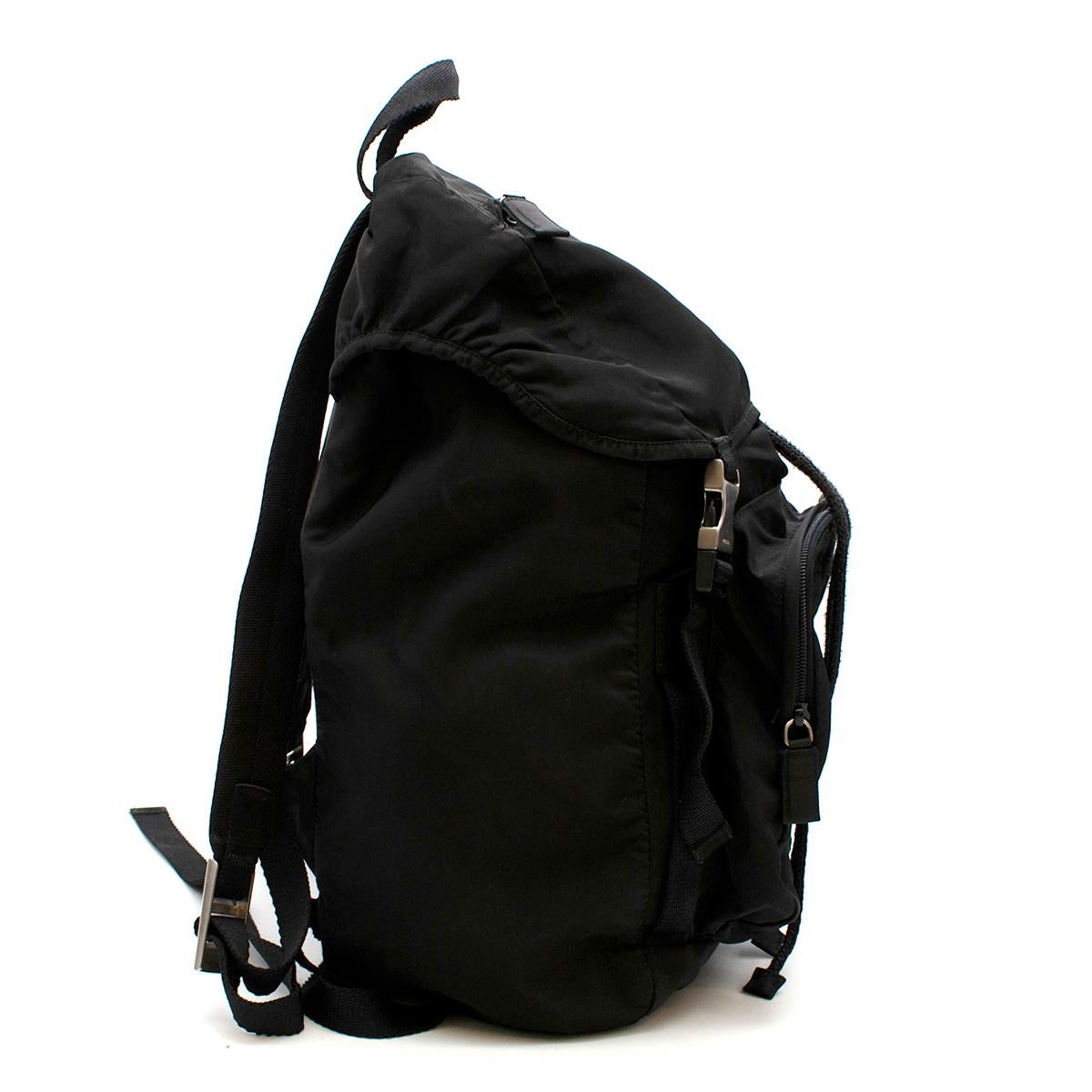 Prada Schwarzer Nylon-Rucksack 

- Hergestellt aus dem für Prada typischen Nylon 
- Verstellbare gewebte Nylongurte
- Emailliertes Metalldreieck-Logo auf der Rückseite 
- Klappenverschluss mit seitlicher Schnalle
- 2 Außentaschen mit