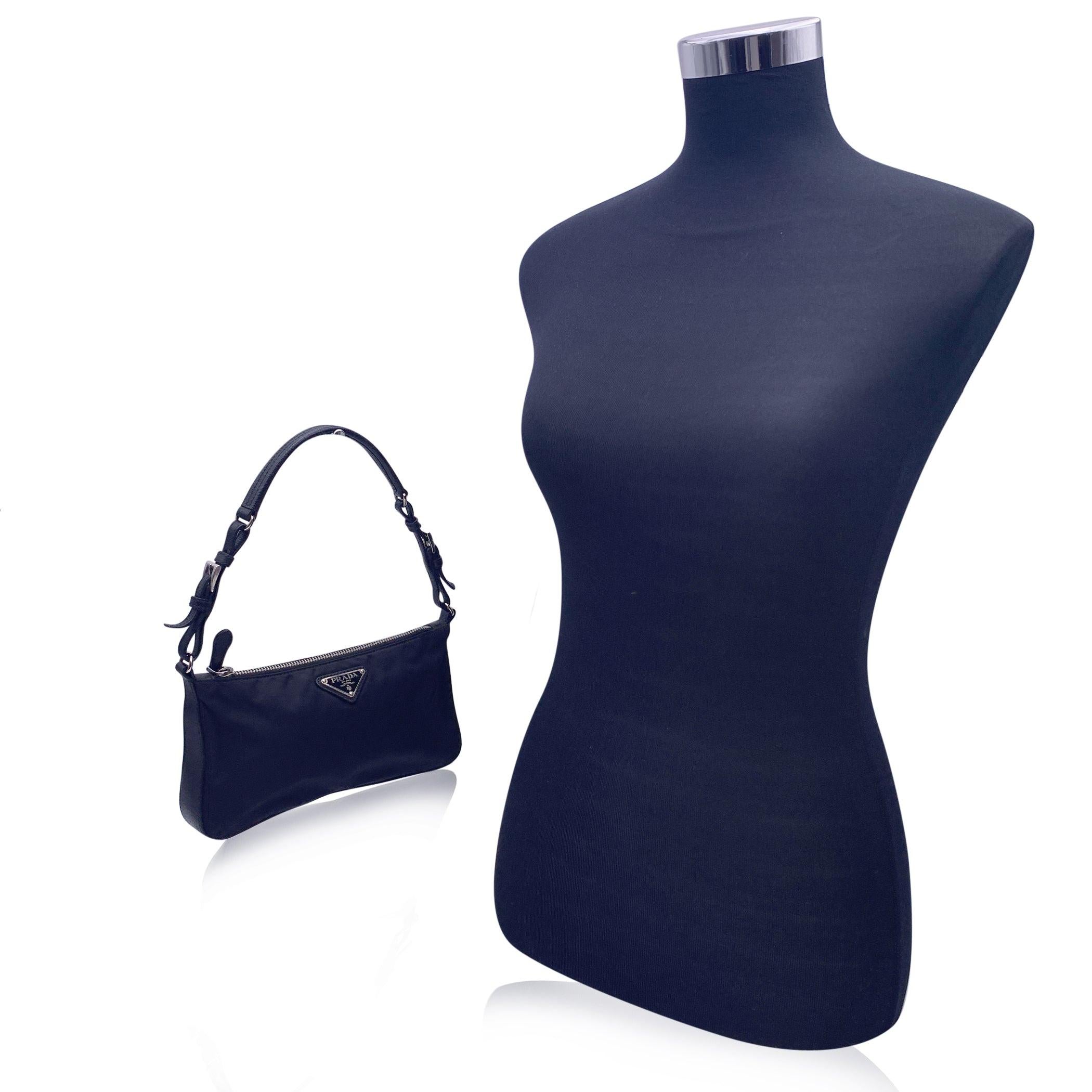 Prada baguette shoulder bag in black nylon canvas. Upper zip closure. Triangle logo in enamelled metal. Black signature lining. 'PRADA Made in Italy' tag inside. Condition B - VERY GOOD Gently used. Some light scratches on leather trim. Strong