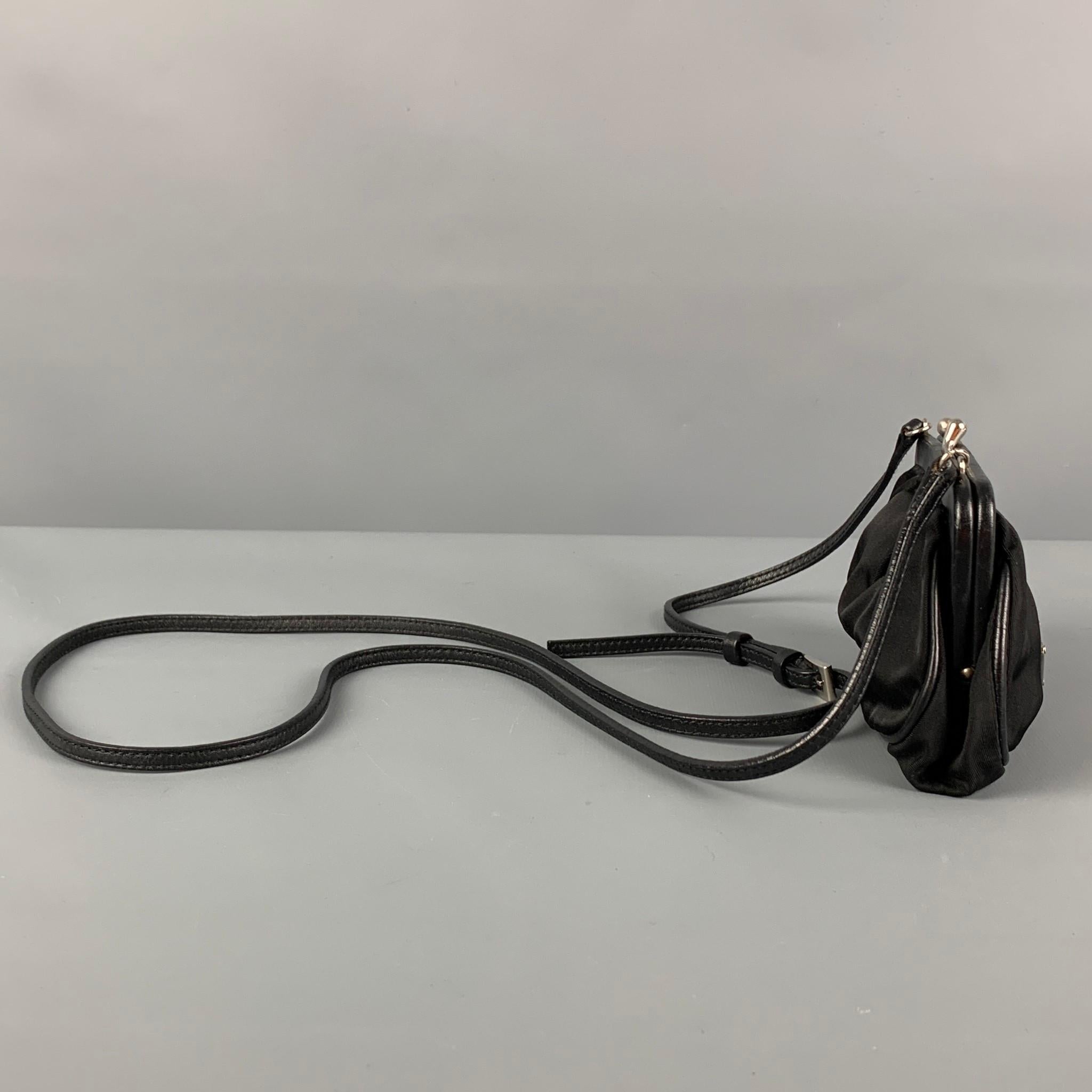 PRADA mini handbag comes in a black nylon featuring a adjustable crossbody strap, logo emblem detail, and a kiss-lock closure. Made in Italy. 

Very Good Pre-Owned Condition. Light wear at strap.

Measurements:

Length: 6 in.
Width: 1.5 in.
Height: