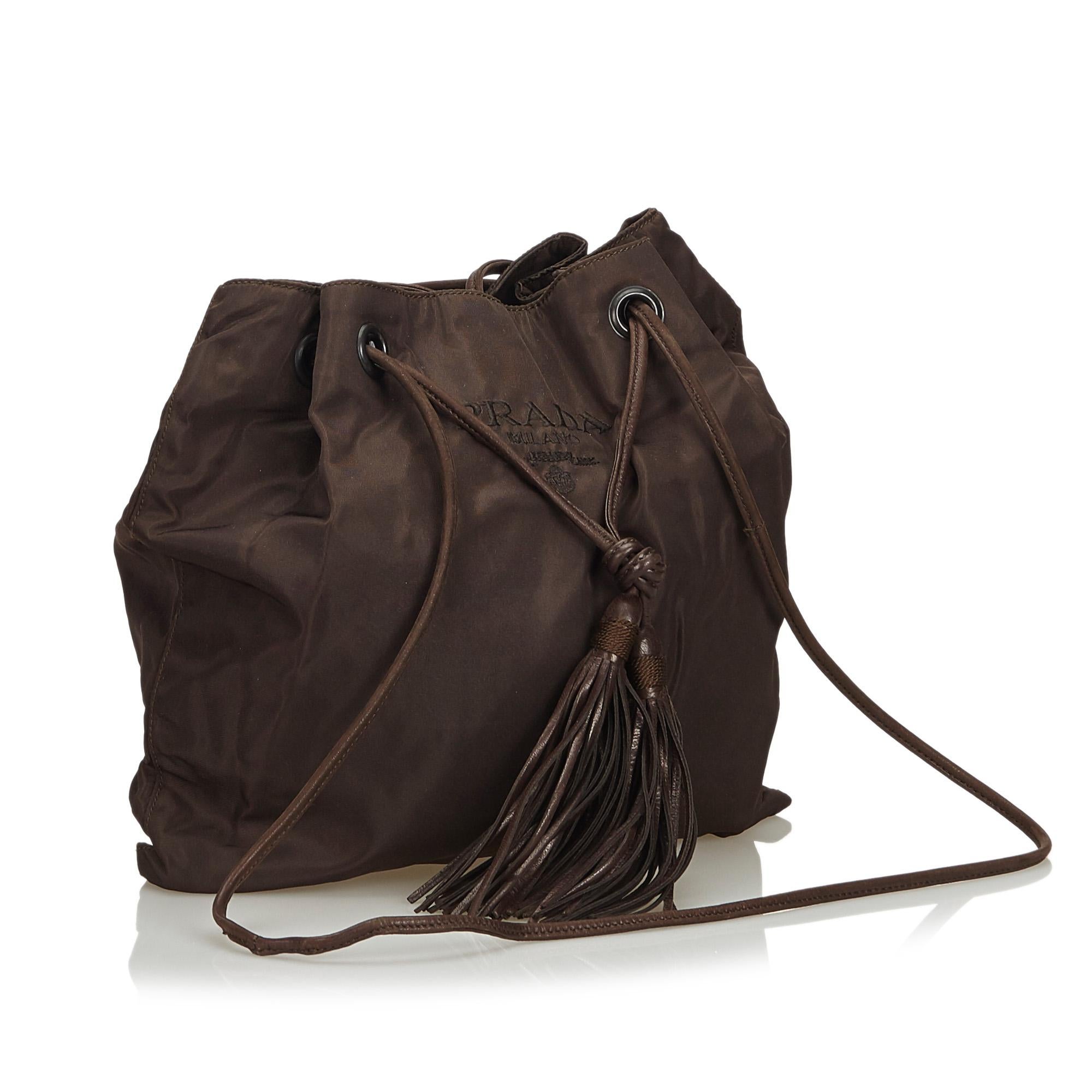 This crossbody bag features a nylon body, a leather tassel detail, rolled leather straps, a drawstring closure, and an interior zip pocket. It carries as B+ condition rating.

Inclusions: 
This item does not come with