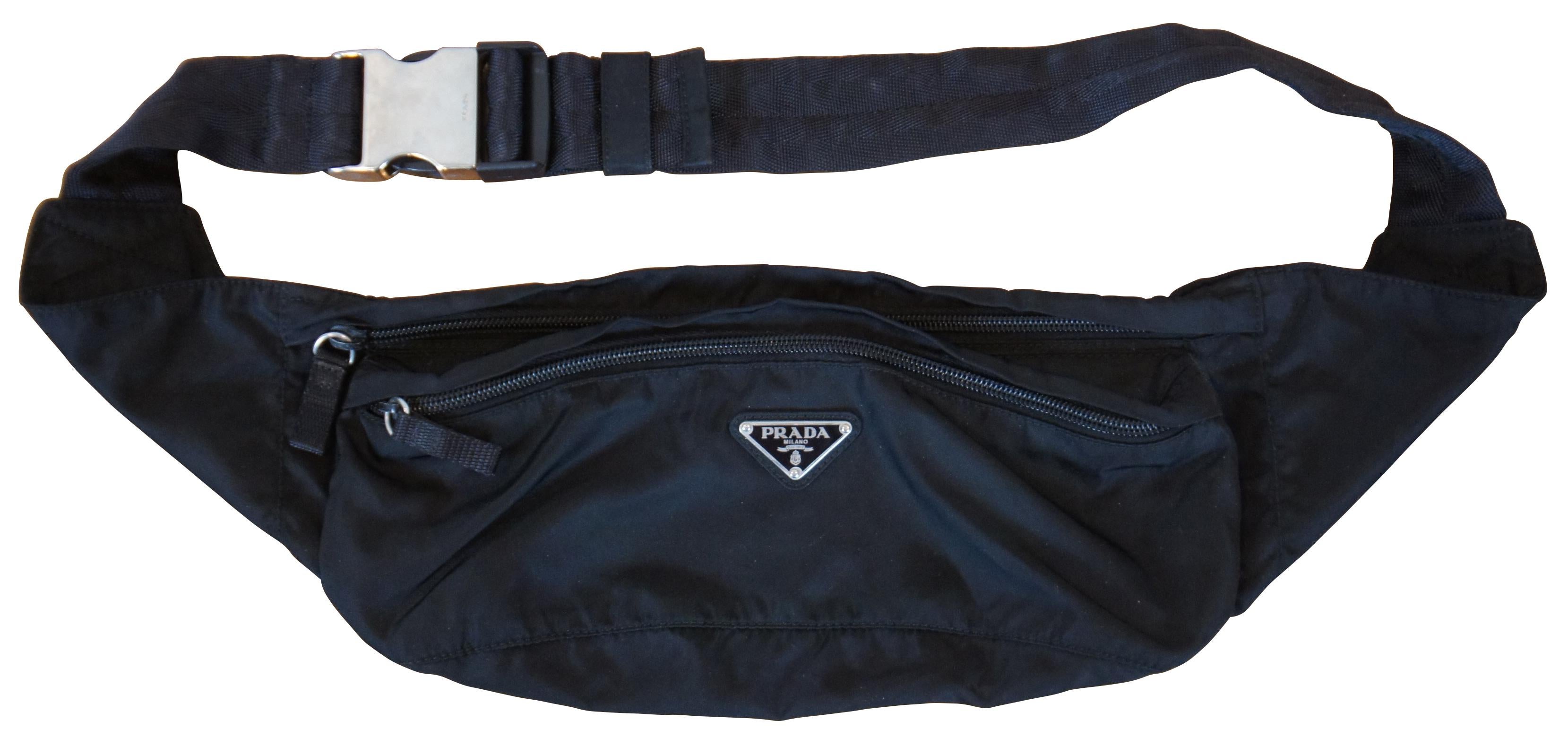 Prada black nylon wait pouch or fanny pack with two zippered compartments and silver tone buckle.

Measured with Belt at Longest - 43” x 3.5” x 5” (Length x Width x Height).