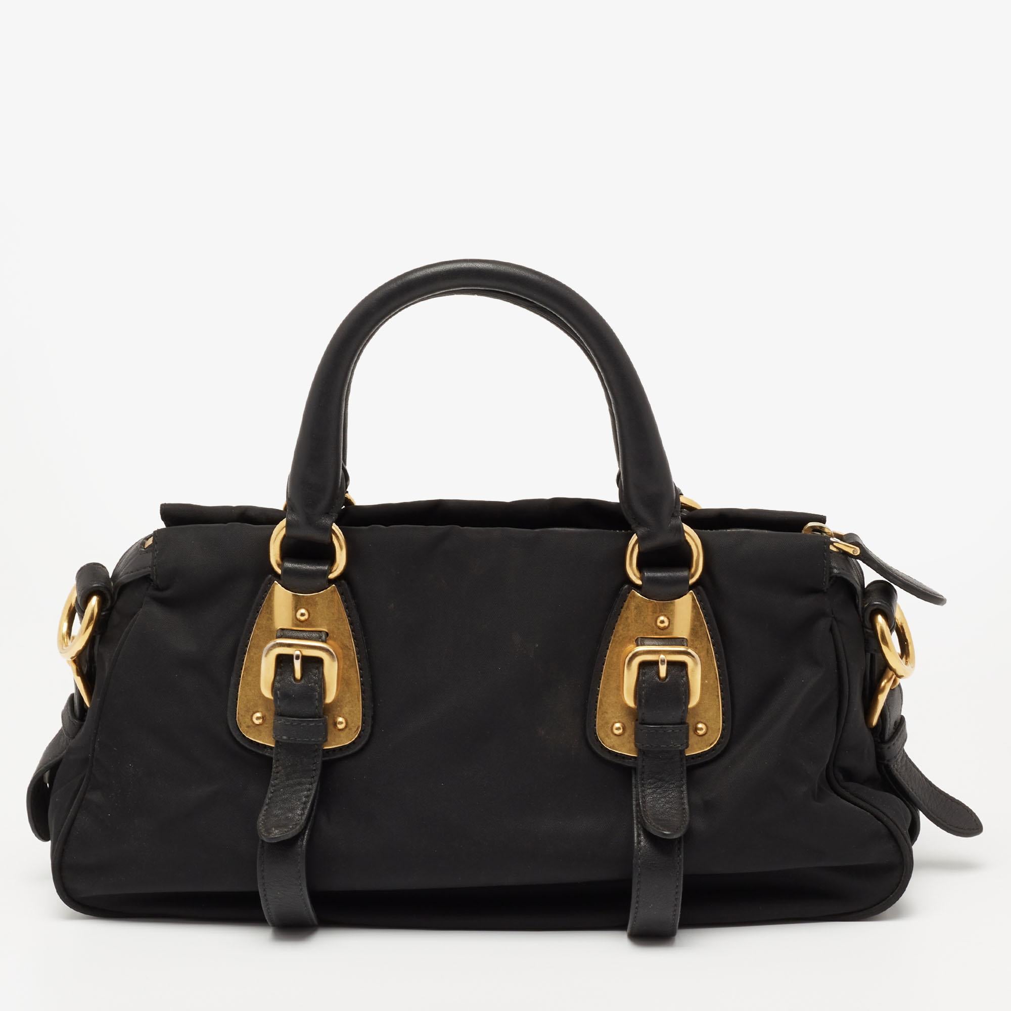 This Gaufre Chain tote from the House of Prada is designed to lend elegance and poise. It is made from black nylon on the exterior. It flaunts a logo accent on the front, a roomy fabric-lined interior, and dual handles. It is fitted with gold-tone