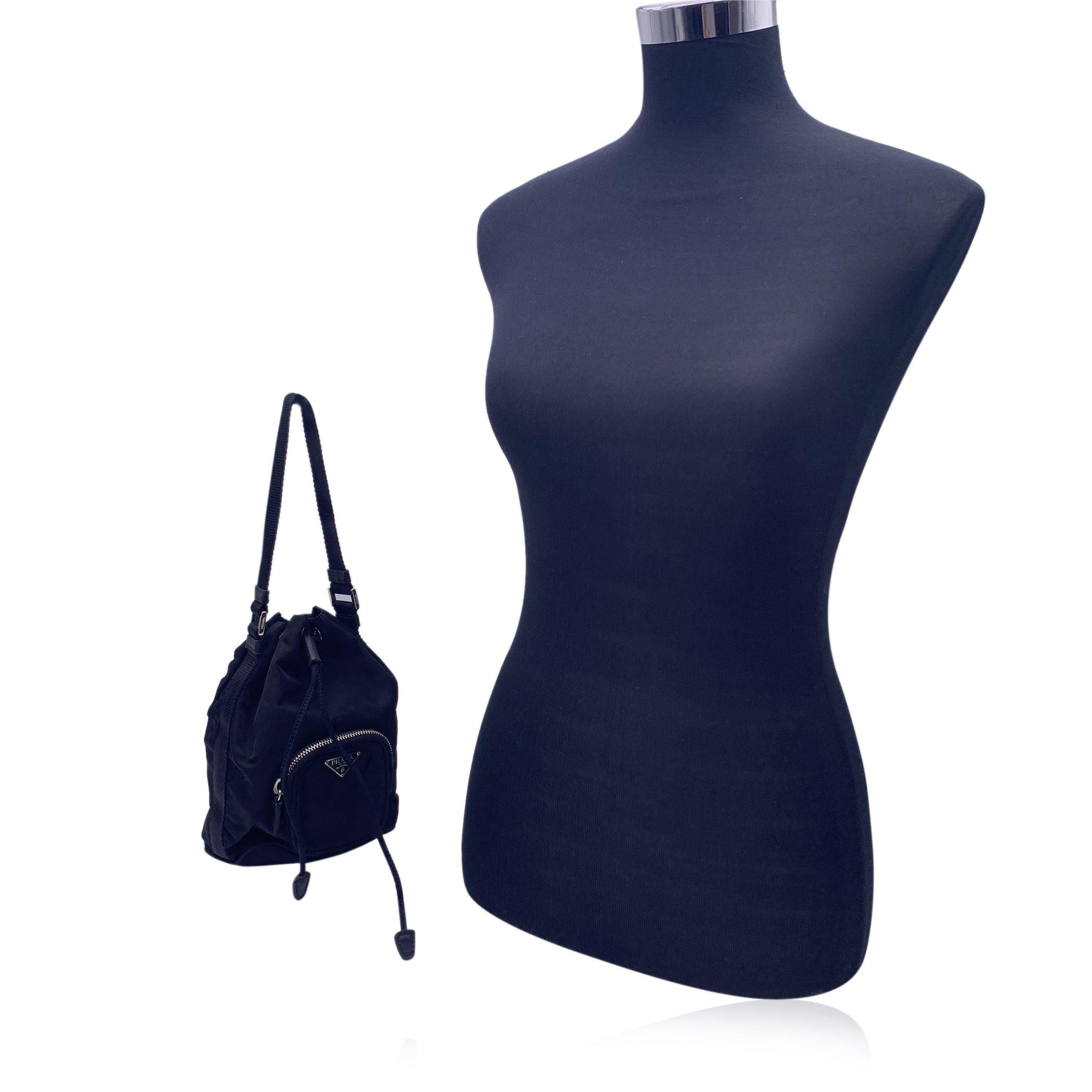 This beautiful Bag will come with a Certificate of Authenticity provided by Entrupy. The certificate will be provided at no further cost. Prada Duet mini bucket bag in black Tessuto nylon canvas. It features drawstring closure, 1 small zip pocket on