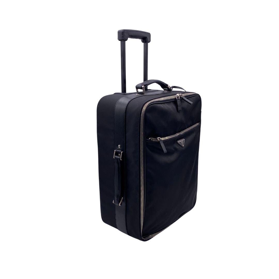 Gorgeous Prada Rolling Luggage Trolley travel bag. Black nylon, saffiano leather trim and fabric lining. Prada triangle logo on the front. Silver metal hardware. Double zipper closure. 1 front zip pocket and 1 rear zip pocket . Top handle and side