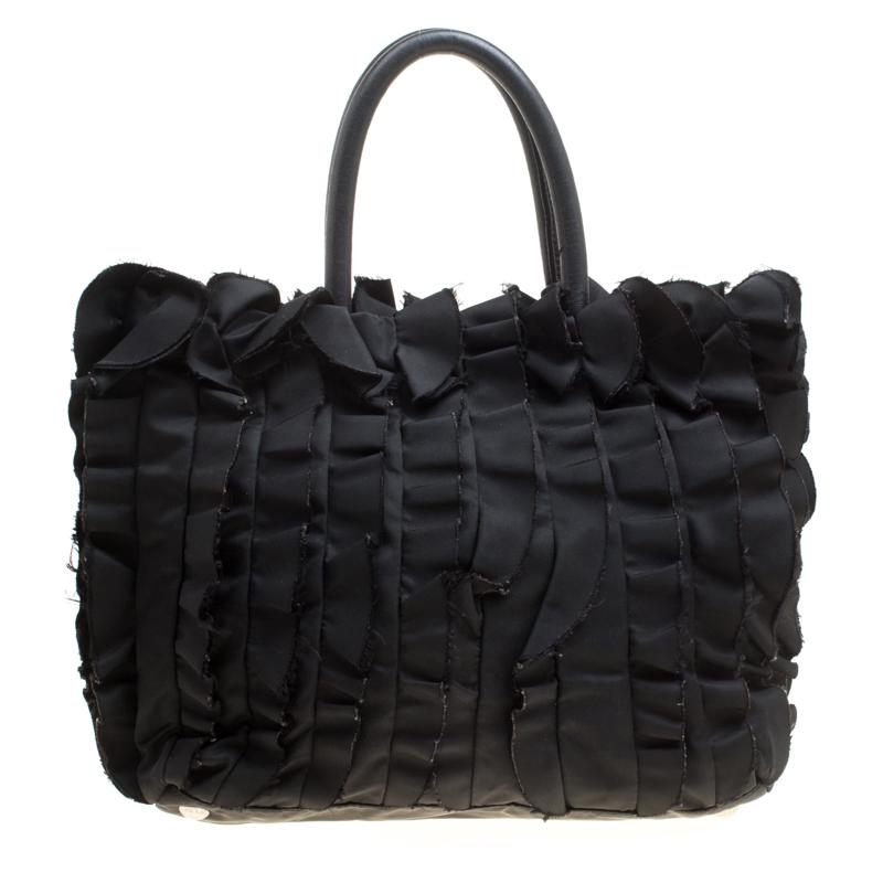 A single look at this pretty Prada creation will steal your heart away. Rendered in black nylon, the tote is designed with utterly feminine aesthetics featuring ruffled patterns all over. The snap button closure on the top leads you to a nylon-lined