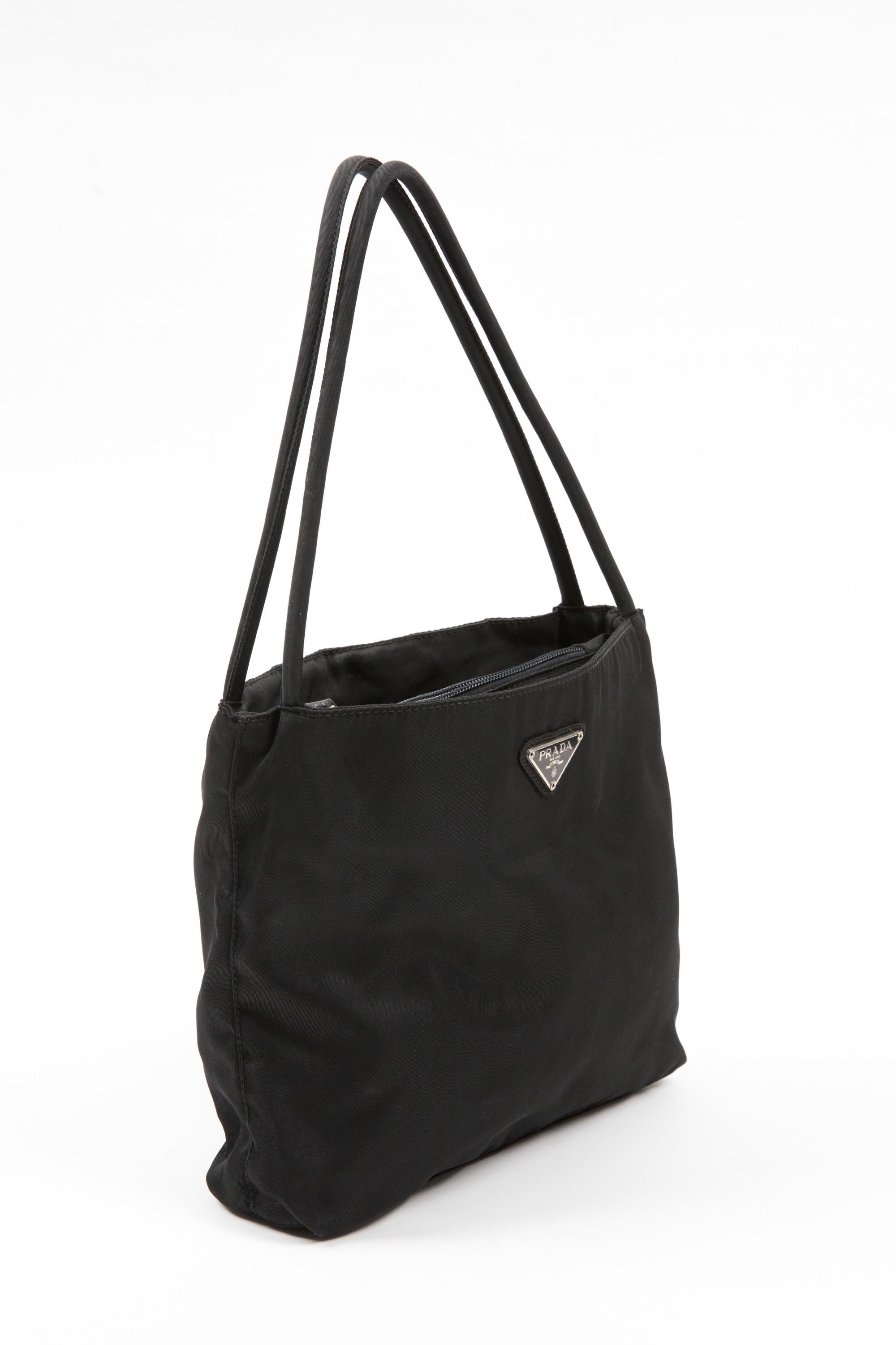 Prada Black nylon Tessuto handbag featuring the enameled metal triangle logo on the front, top handles, a compartment with top zipper closure and interior logo lining. 
Circa 2000s. 100% Nylon
In good vintage condition. Made in Italy.
Length: 8.6in.