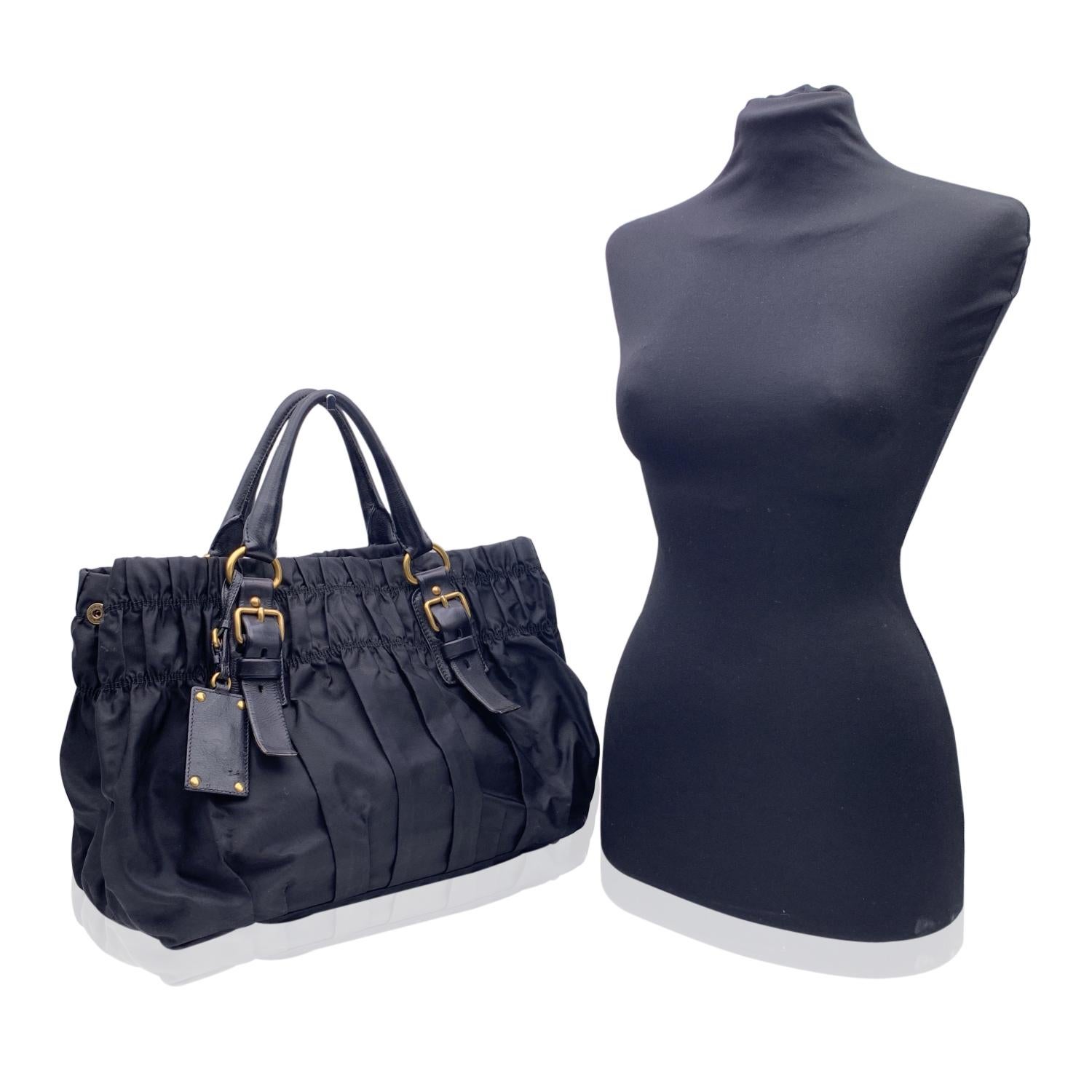 Prada black leather draped tote bag. Black pleated nylon and black leather handles and trim. Gold metal hardware. Button closure on top. Prada signature lining. 2 side zip pockets inside. 'Prada - Milano' tag inside. Small tag with code