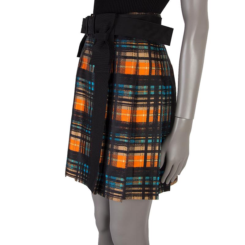 Prada plaid pleated skirt in black, orange, blue, yellow, and sand wool (52%) and silk (48%). With two vertical bows on the front and belt loops. Closes with hook and invisible zipper on the side. Lined in black cupro (60%) and silk (40%). Comes
