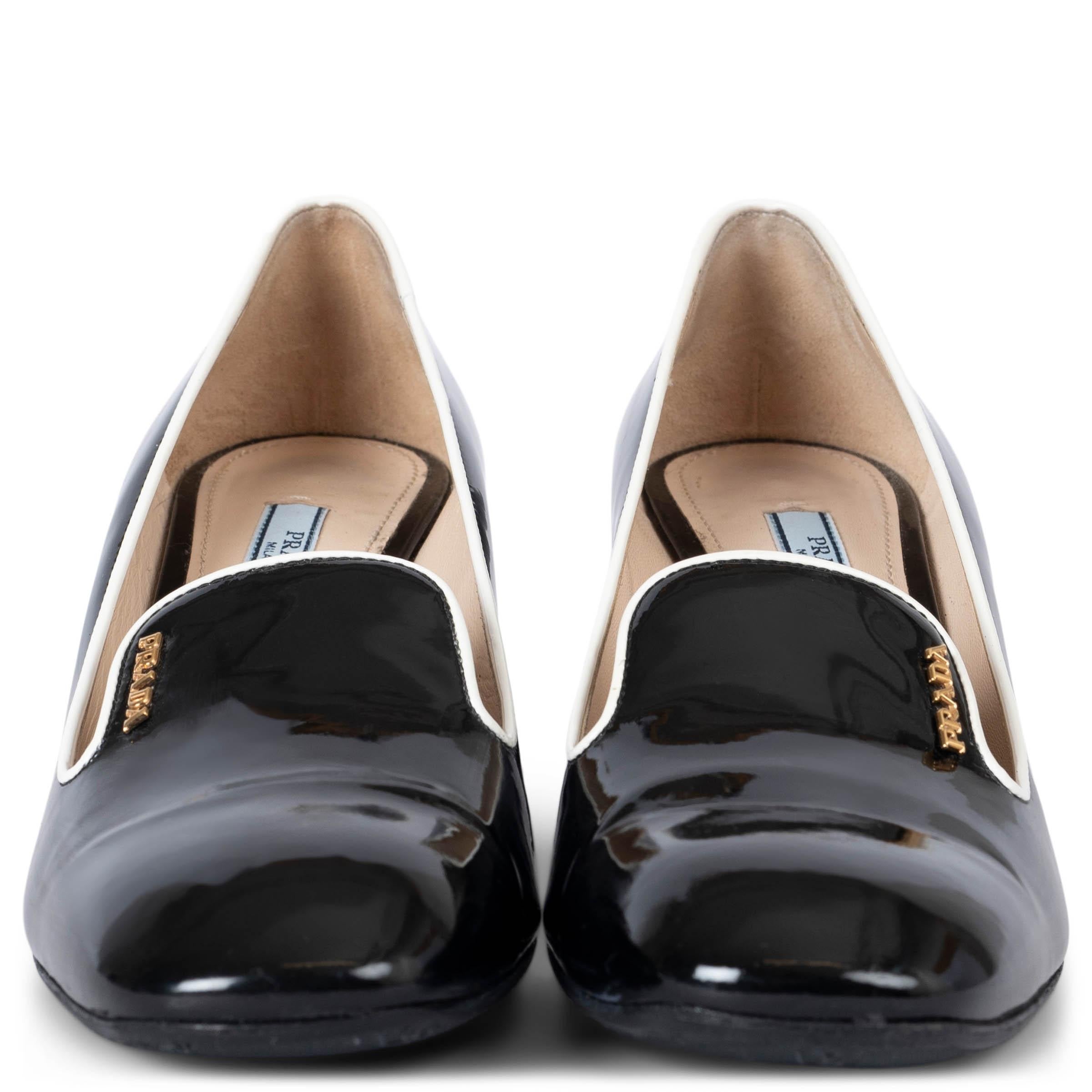 These 100% authentic Prada pumps are crafted from black patent leather, inspired by smoking loafers. They feature a squared toe, contrasting white piping, a block heel, and a metal logo detail, offering a sophisticated yet modern look perfect for