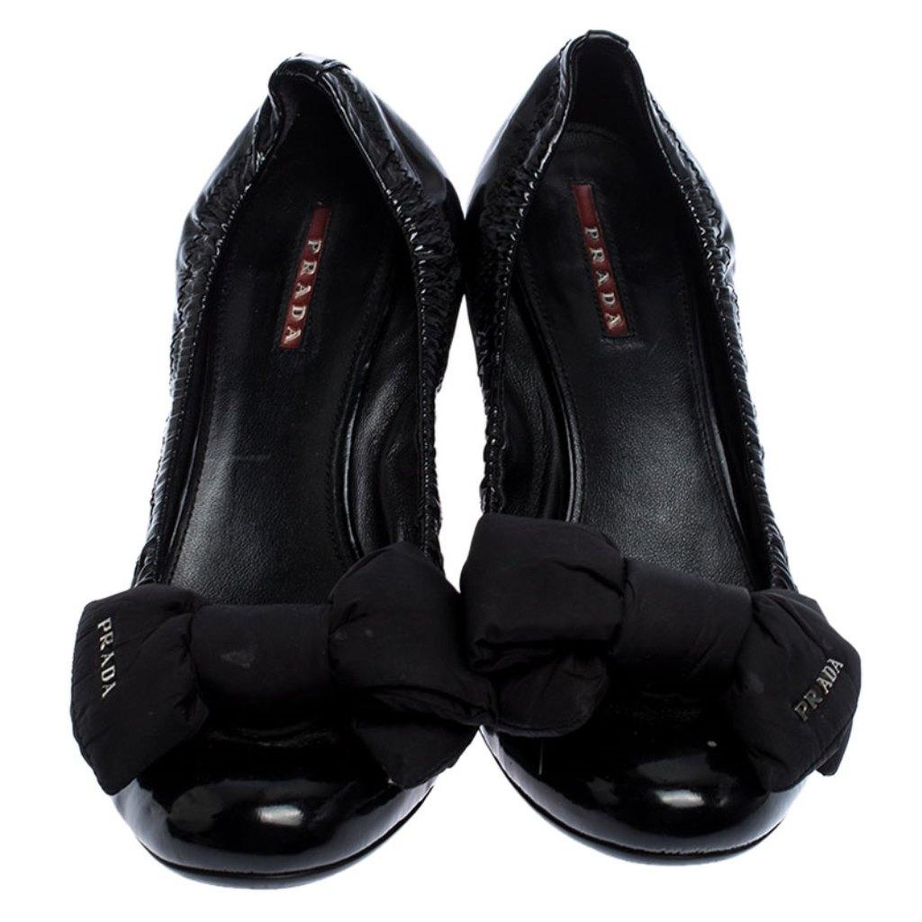 Add a dash of glam to your everyday outfit with this pair of gorgeously designed Prada pumps. Look fabulous in this pair of pumps, crafted out of patent leather and designed with satin bows on the vamps and low block heels. The exquisite design of