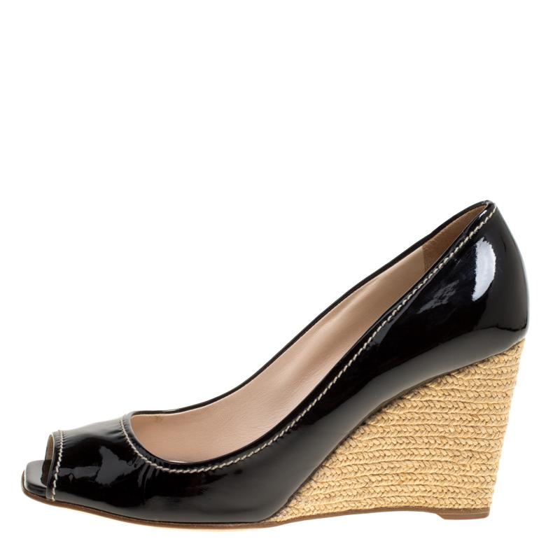 Feminine and classy, these pumps by Prada are just irresistible. They carry a glossy black exterior made from patent leather and styled with peep toes. Leather insoles and espadrille wedges wonderfully complete the pair.

Includes: Original Dustbag

