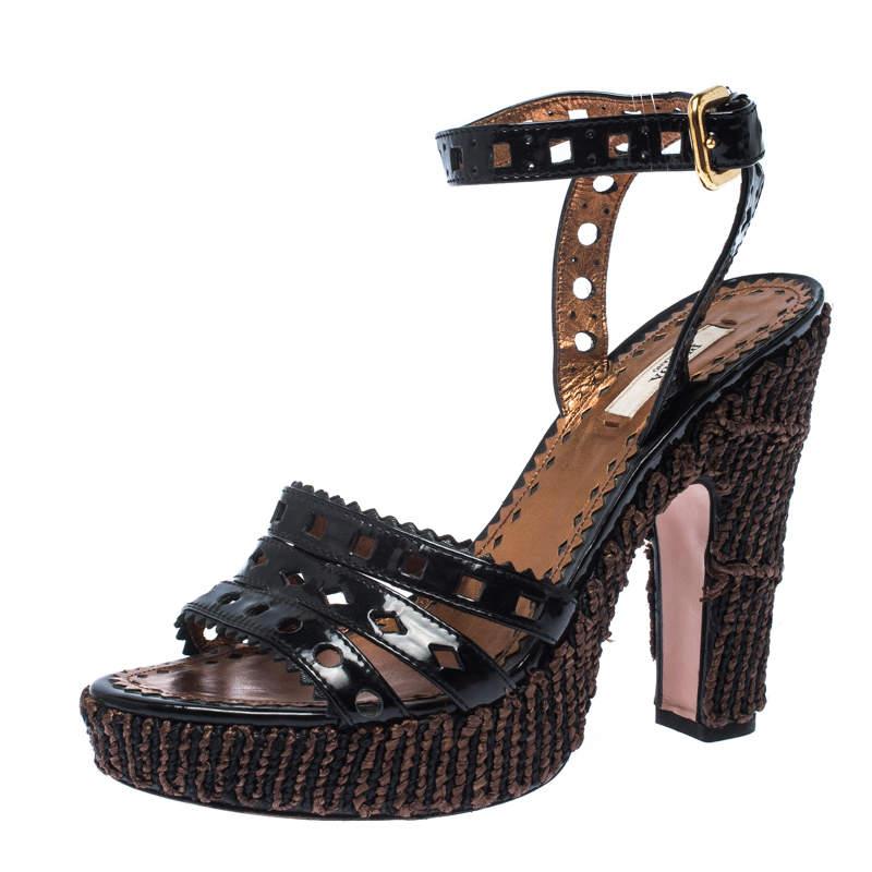 The house of Prada brings you these impressive sandals that complement any outfit. The pair has a bevy of features that make it simply irresistible. The straps are fashioned out of patent leather complementing the elegant raffia body with a platform