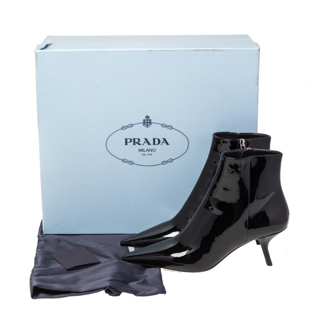 A feminine flair, sleek cuts, and a timeless appeal characterize these stunning Prada boots. Skillfully crafted from black patent leather, they are designed into a pointed-toe silhouette. The pumps are raised on low slanted heels and secured with