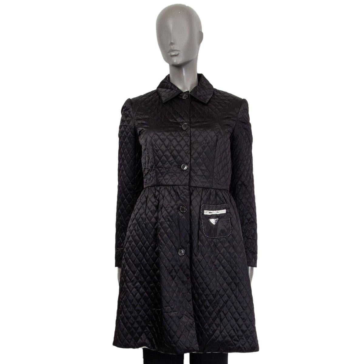 
100% authentic Prada quilted belted trench coat in black polyamide (100%) with a cut at the waist-line and a small zipped pocket with logo-tag on the front. Closes with six buttons and with a belt on the front. Lined in light gray polyamide (100%).