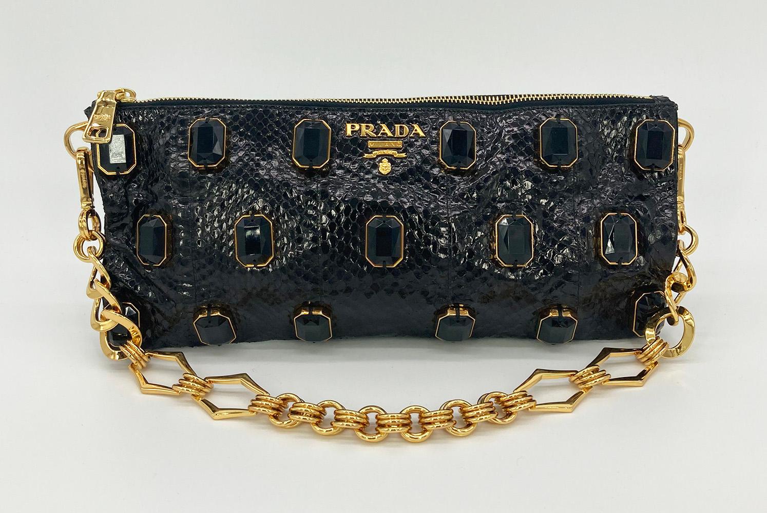 Prada Black Python Whips Pietre Clutch in excellent condition. Black python snakeskin exterior trimmed with gold hardware and large black crystal embellishments along front side. Top zipper closure opens to a black leather interior with one side
