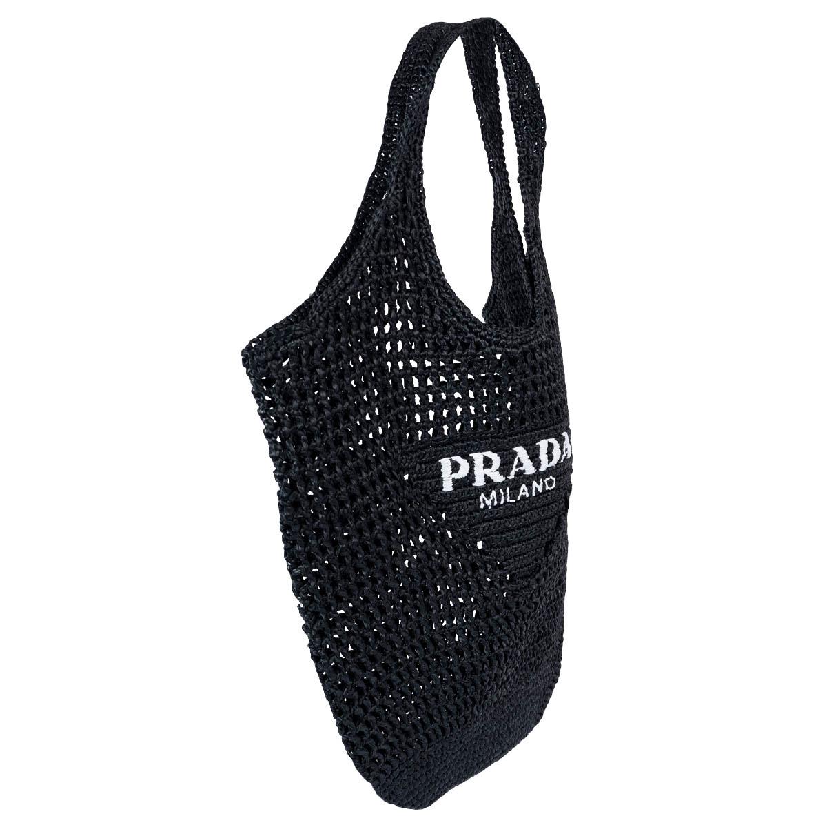 100% authentic Prada Logo crochet tote bag with a soft, deconstructed design made of raffia-effect yarn. The embroidered white lettering logo decorates the front of this accessory that reinterprets the beach bag concept in a new and contemporary