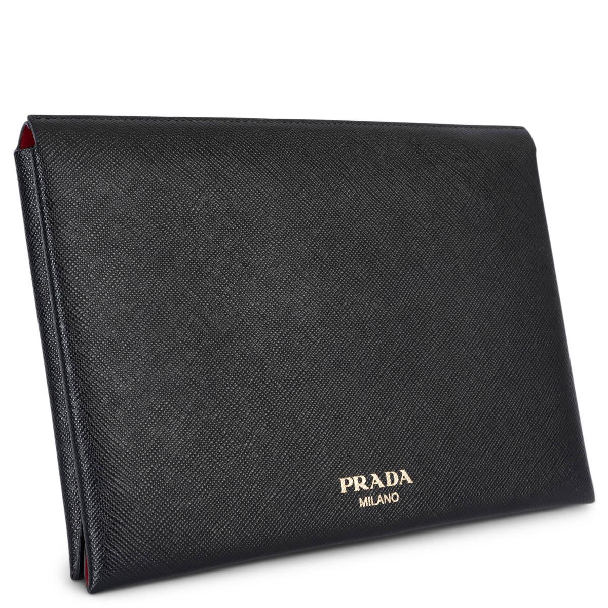 100% authentique Prada petite pochette porte-documents enveloppe en cuir Saffiano noir. Il s'ouvre par un bouton poussoir et est doublé en cuir Saffiano rouge et en cuir de veau. L'intérieur comporte une pochette amovible à fermeture éclair de