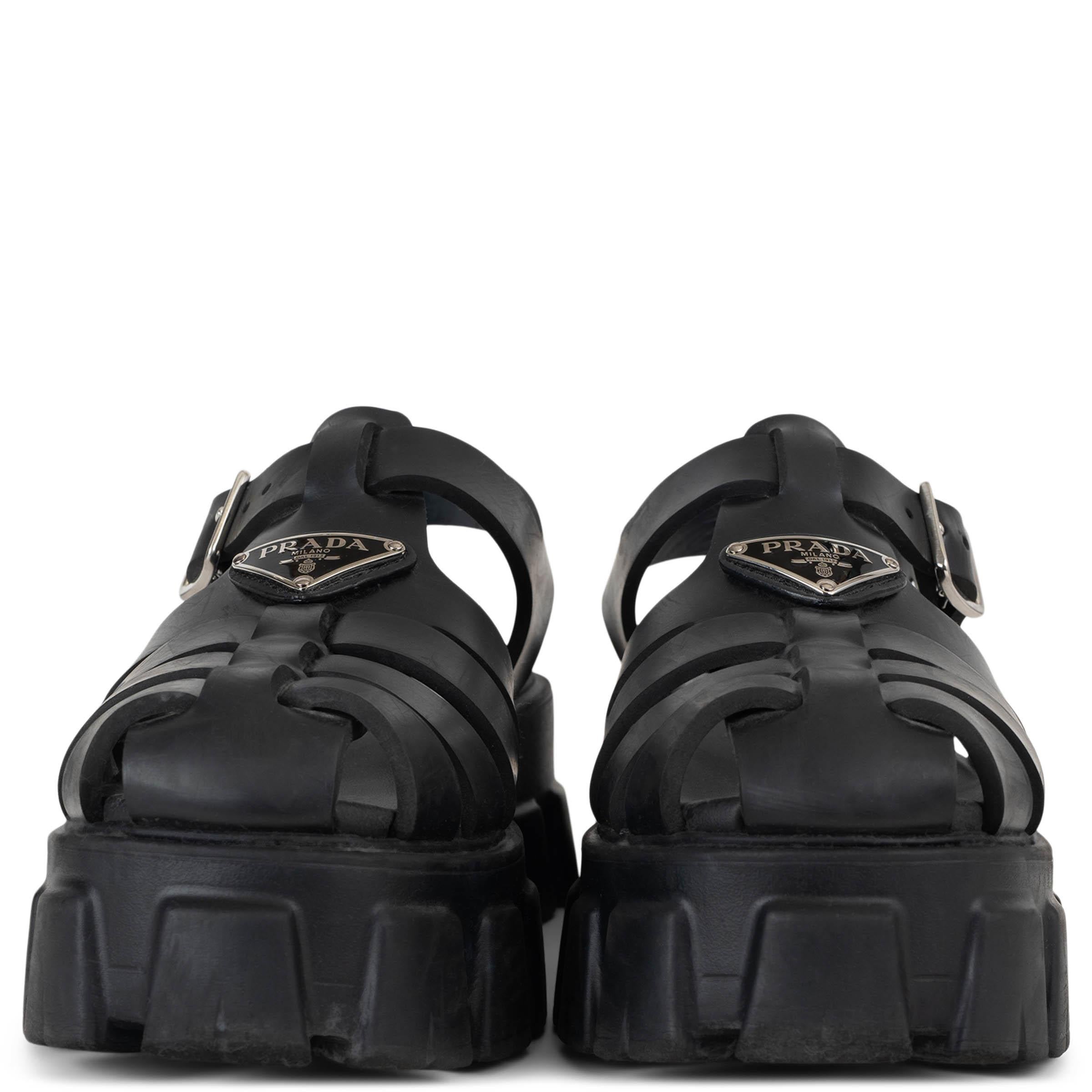 This 100% authentic Prada Monolith fisherman sandal in black rubber is a bold reimagining of a classic silhouette. Featuring rounded toes with a signature enamelled triangle logo plaque across the top, the design is grounded in Prada’s iconic chunky