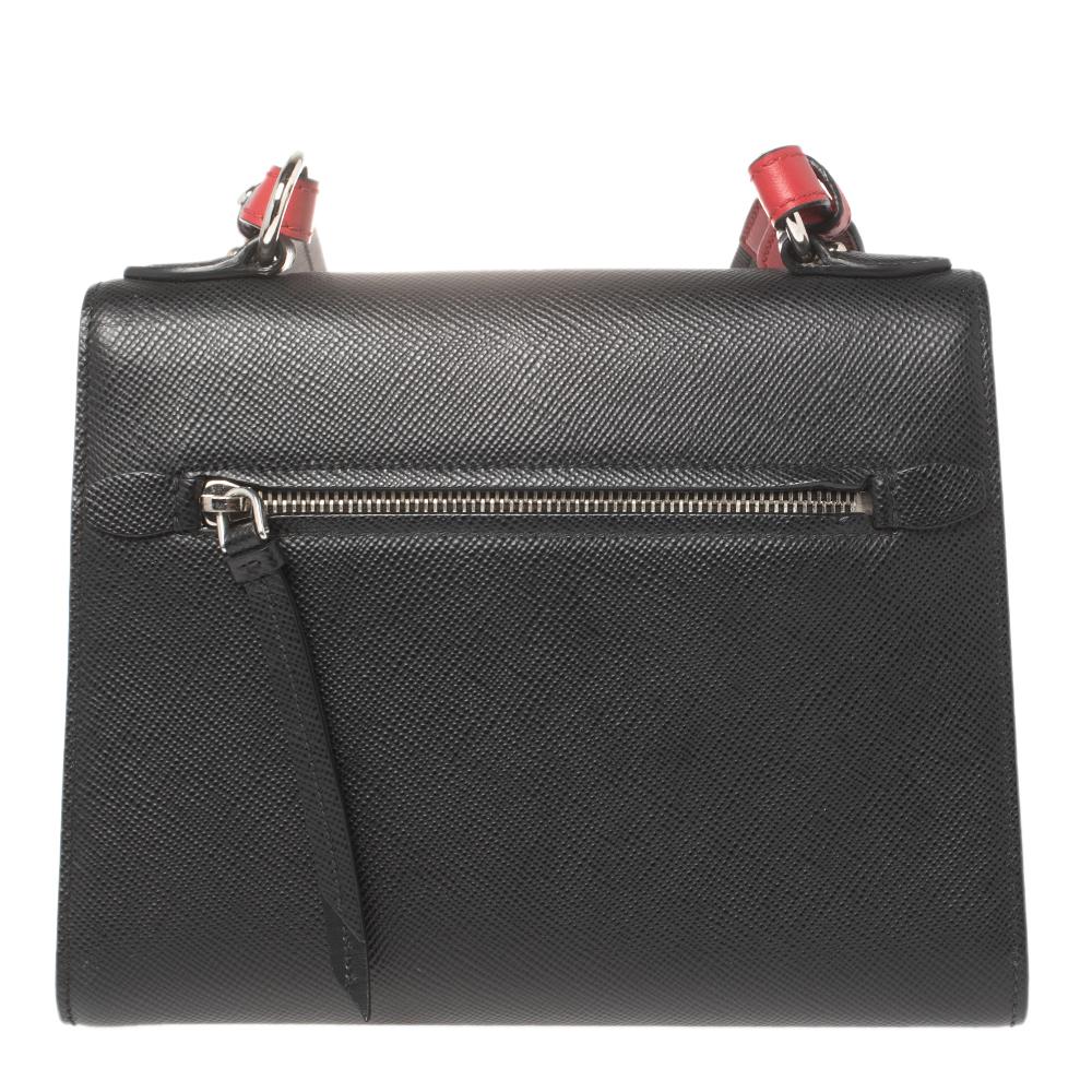 High on style, carry this Monochrome bag from Prada without compromising on style. Look stunning with this bag crafted from quality leather. It has a front flap carrying the brand logo. It opens to a spacious nylon-lined interior with a zip pocket