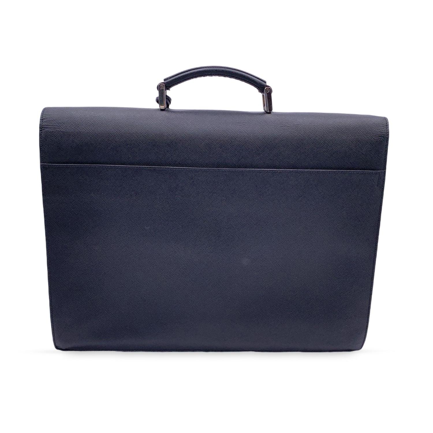 Prada Saffiano leather briefcase with 3 gussets. Polished steel hardware. Leather lining. Tag logo on the inside and engraved logo on push-lock closure. One handle. Flap with key closure (key is not included). 3 compartments with pleats organized