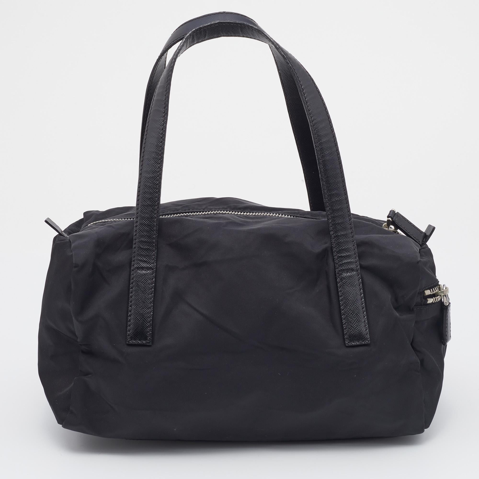 This Prada bag will uplift your style quotient and take it a notch higher. A fine blend of cool style and functionality, this black bag is crafted from a fine blend of materials and has the brand logo on the front along with dual top handles. This