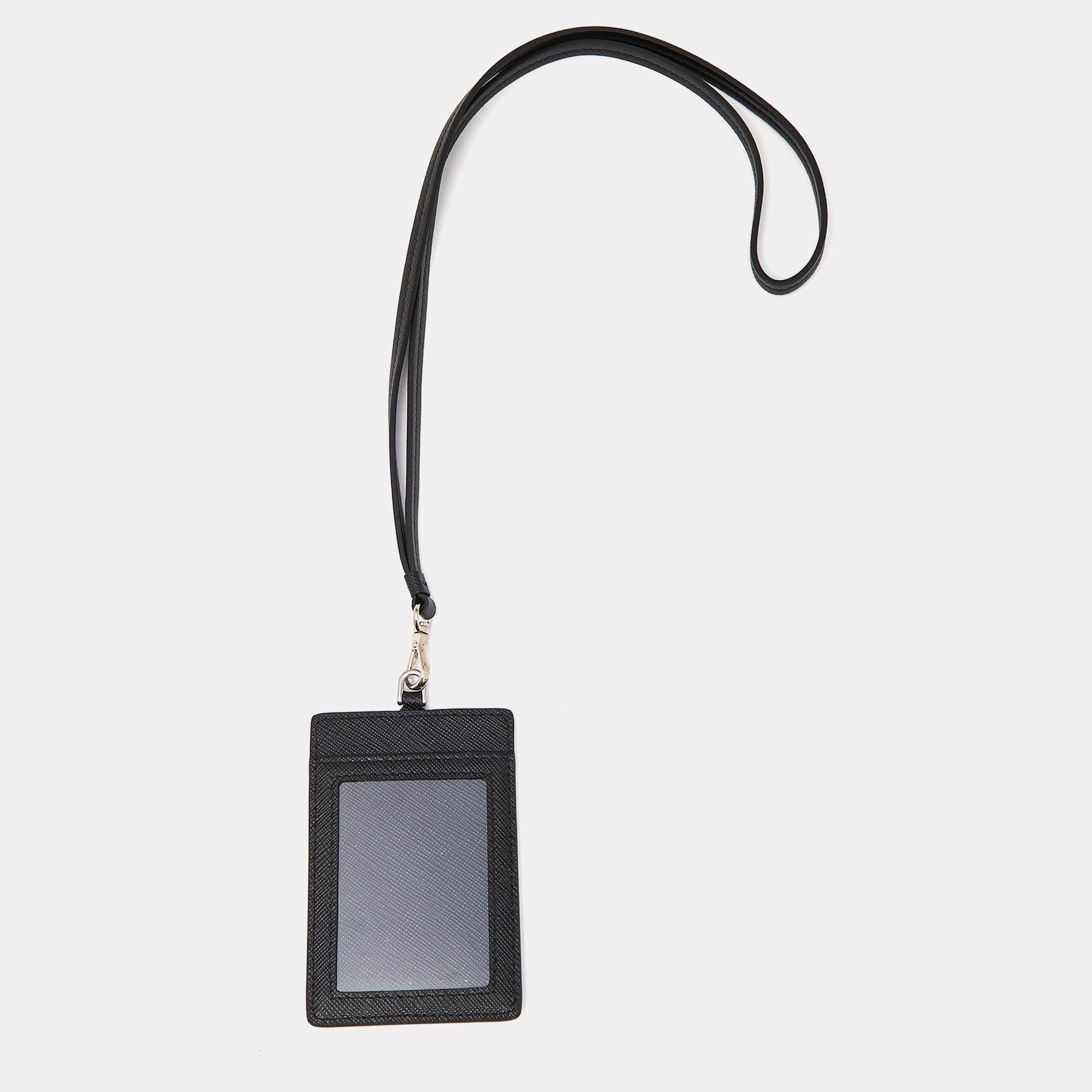 Crafted from luxurious black Saffiano leather, the Prada Badge Holder epitomizes elegance and practicality. Its sleek design boasts a clear ID window and multiple card slots, perfect for organizing essentials with finesse. A discreet Prada logo adds